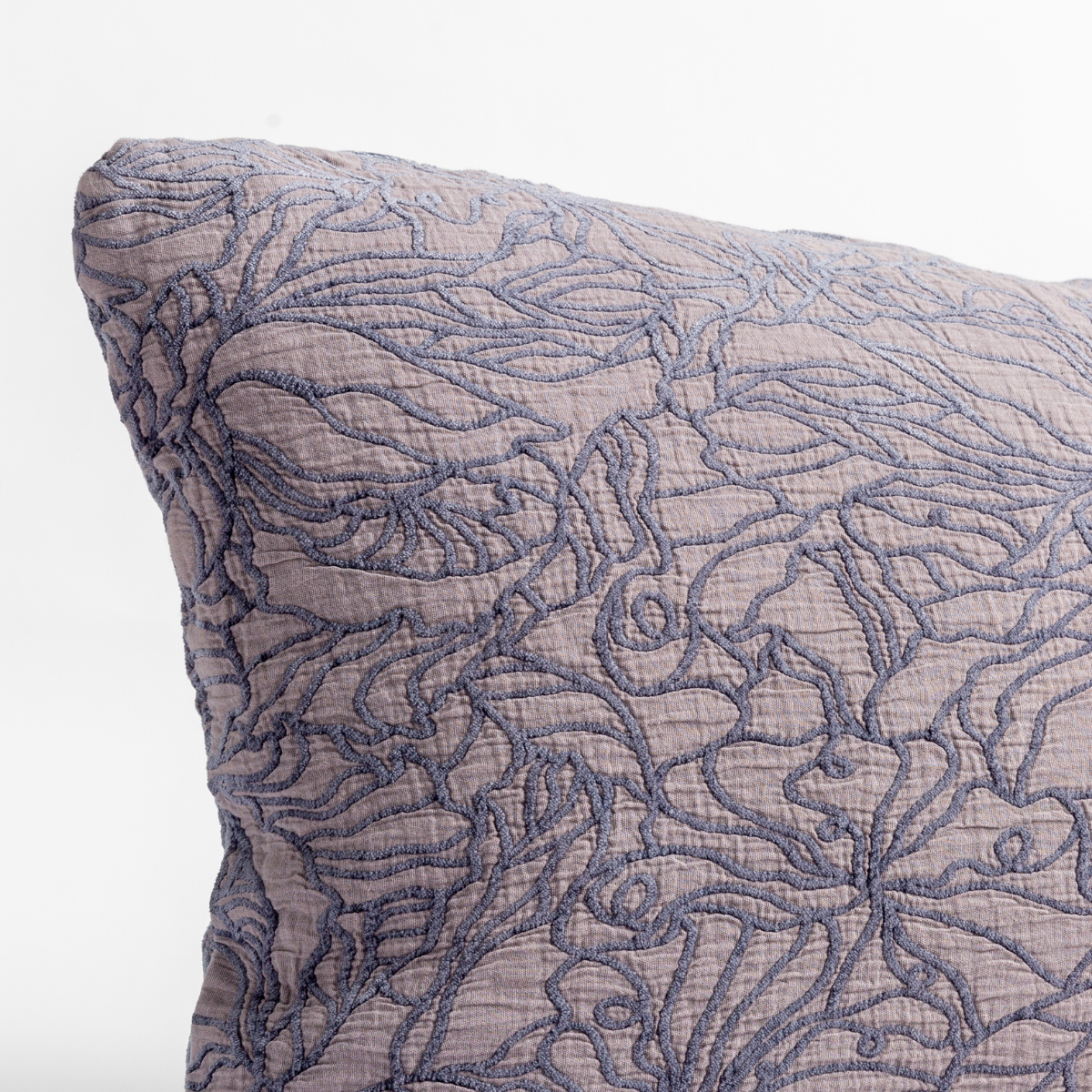 French Lavender: close up of the cotton jacquard corner of a pillow cushion with a single-line floral pattern.