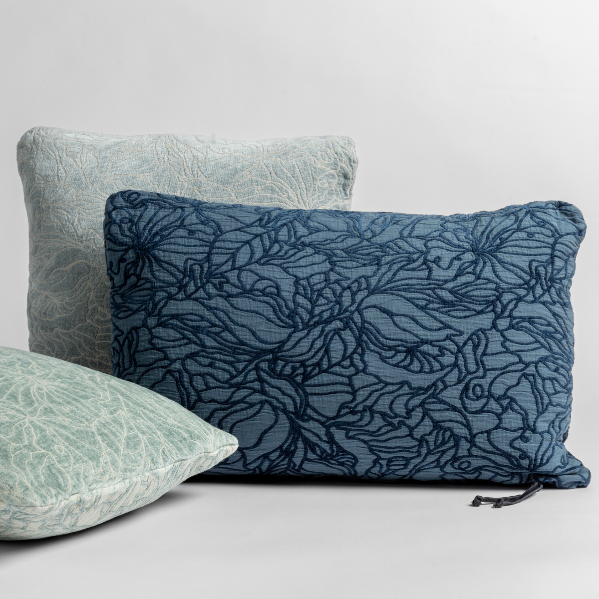 [allvariants]:  throw pillows in different sizes and shapes shown in green and blue tones, the different sides of the pillow show the tonal and pattern contrast. 