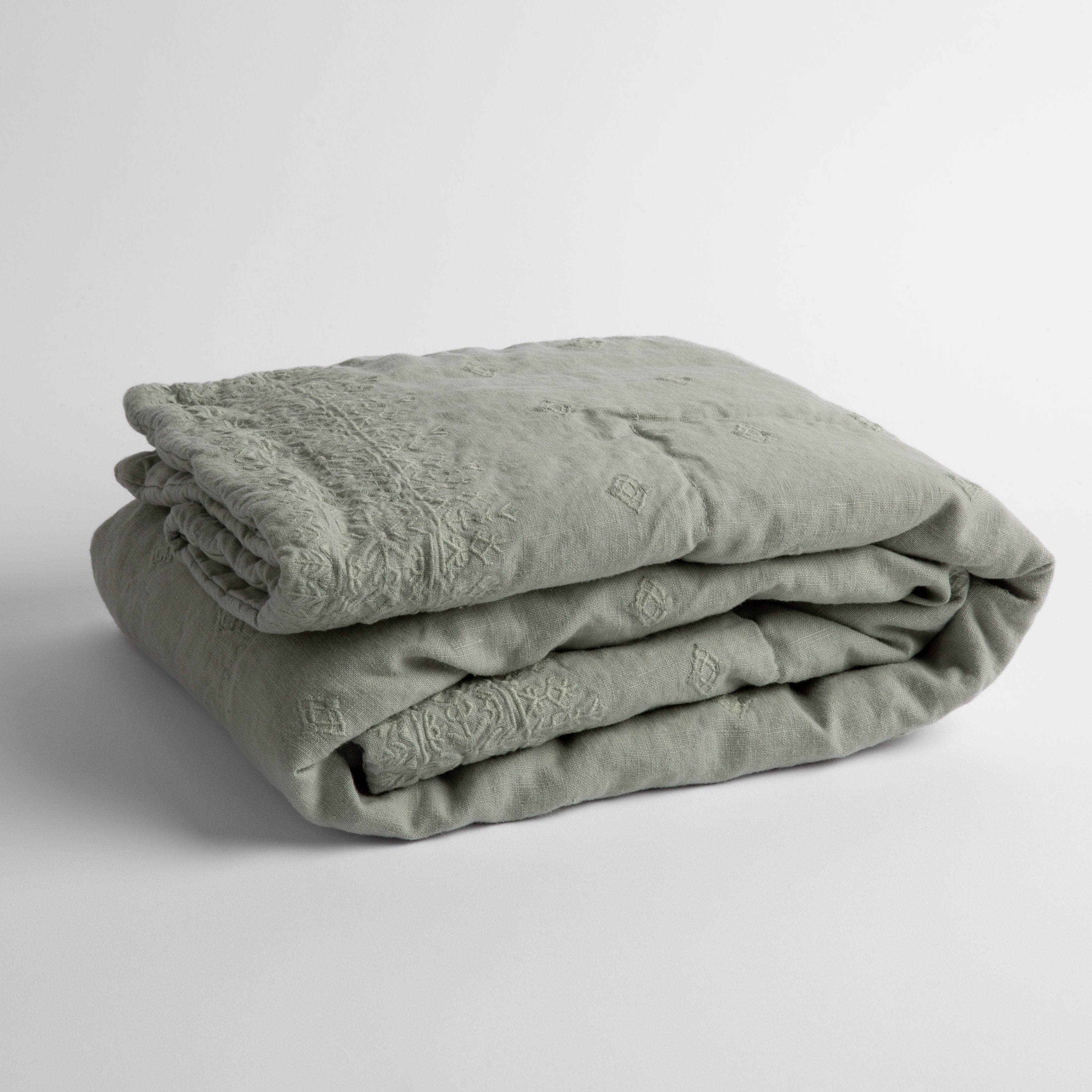 Eucalyptus:  embroidered linen baby blanket folded and shown  overhead from a slight angle against a white background. 