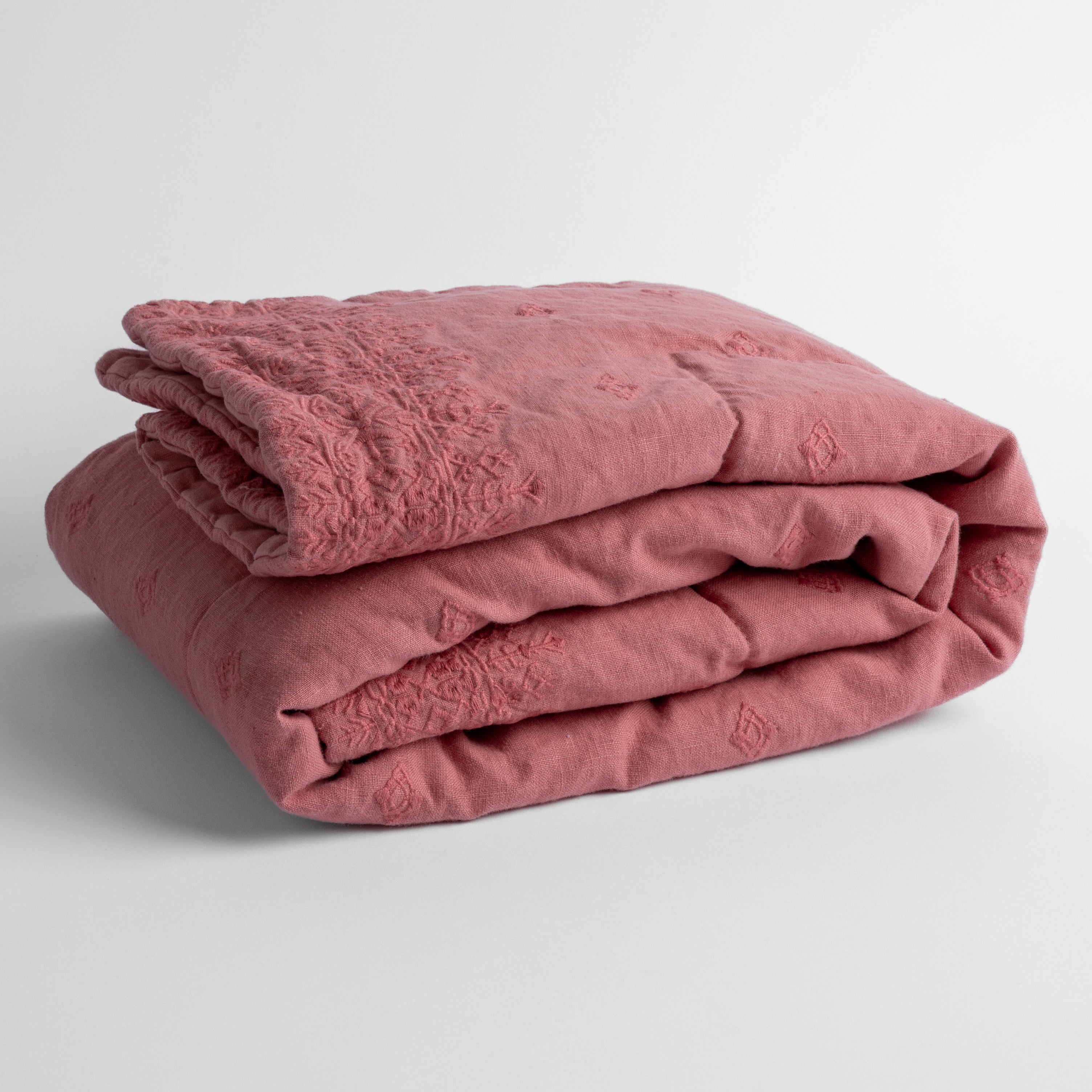 Poppy: embroidered linen baby blanket folded and shown  overhead from a slight angle against a white background. 