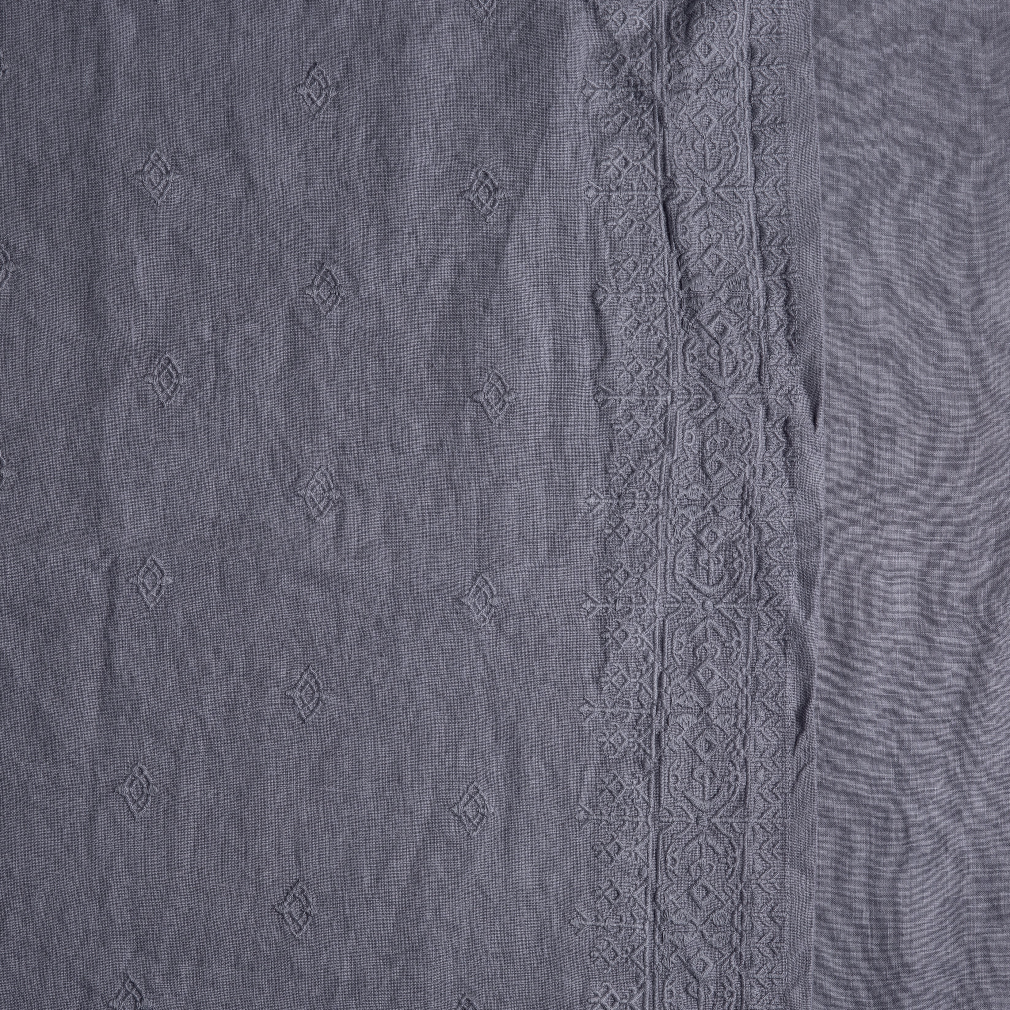 A close up of embriodered midweight linen in french lavender, a neutral lavender tone. 