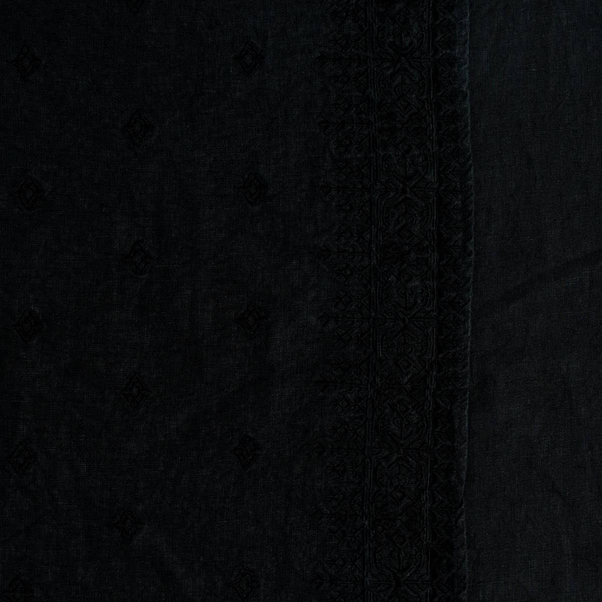 Corvino: A close up of embroidered midweight linen fabric in Corvino, a black tone.
