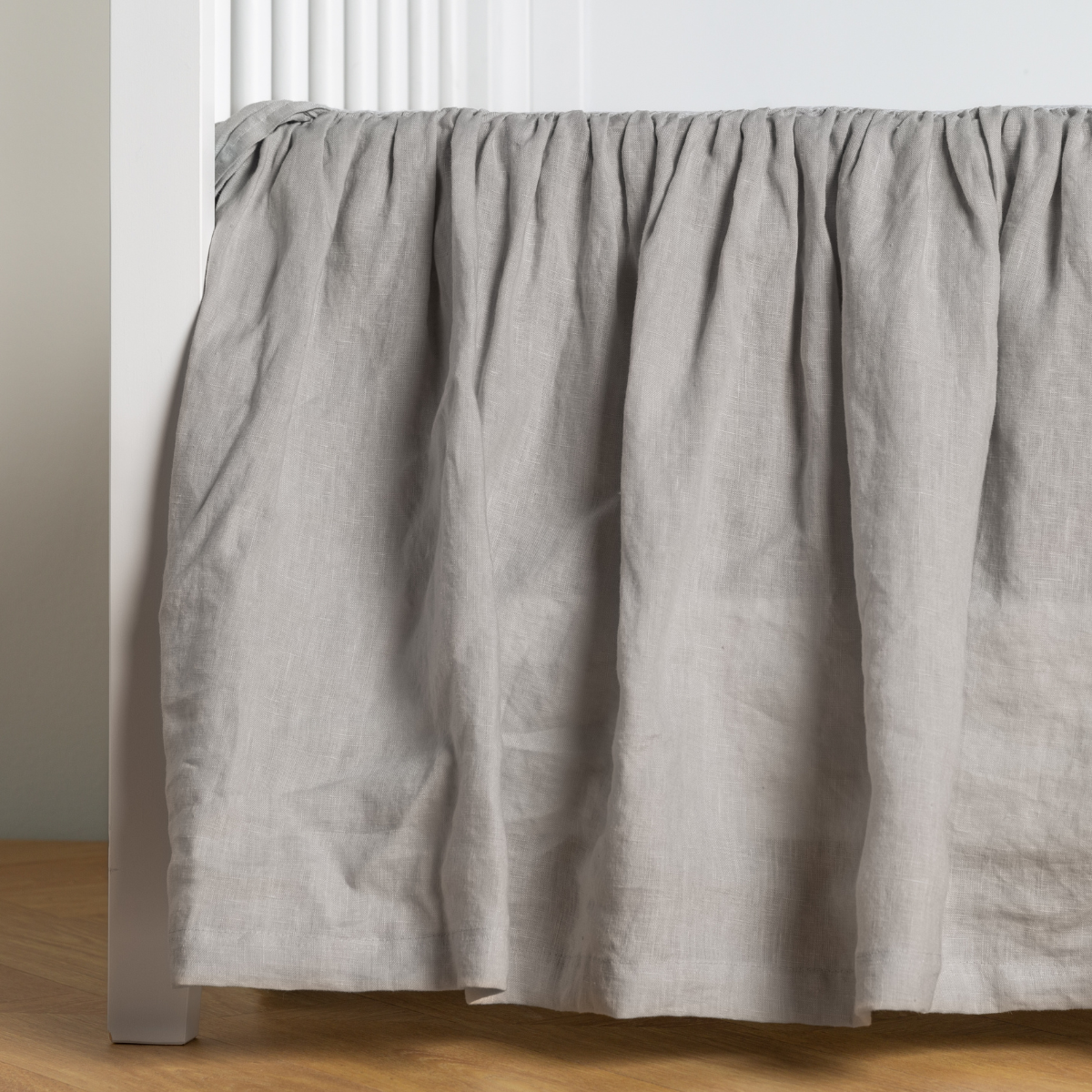 Cloud:  crib skirt shown on a white crib with no mattress against a white wall and medium wood flooring. 