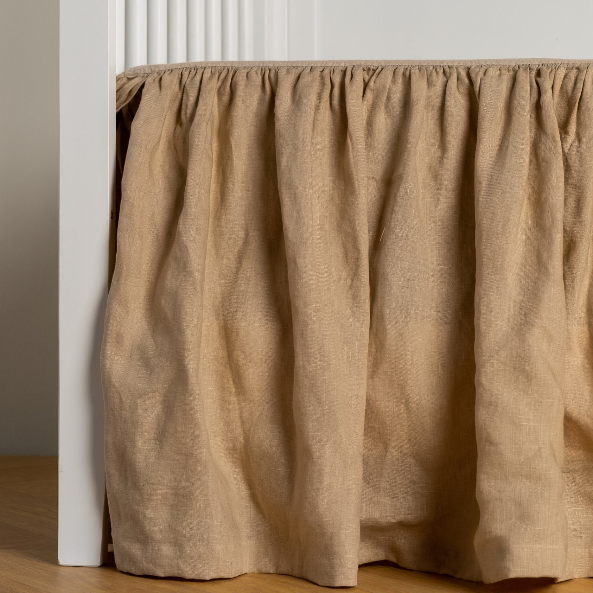 Honeycomb: crib skirt shown on a white crib with no mattress against a white wall and medium wood flooring. 