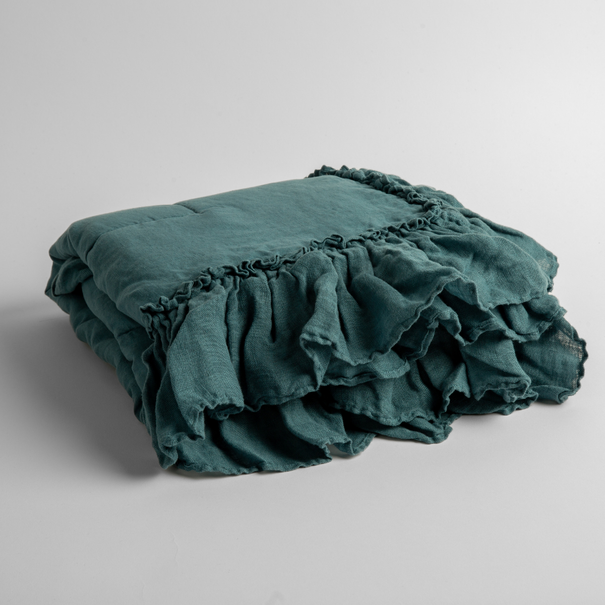 Cenote:  a folded linen with linen whisper ruffled blanket folded and positioned to show the ruffle detail against a white background and slightly overhead. 