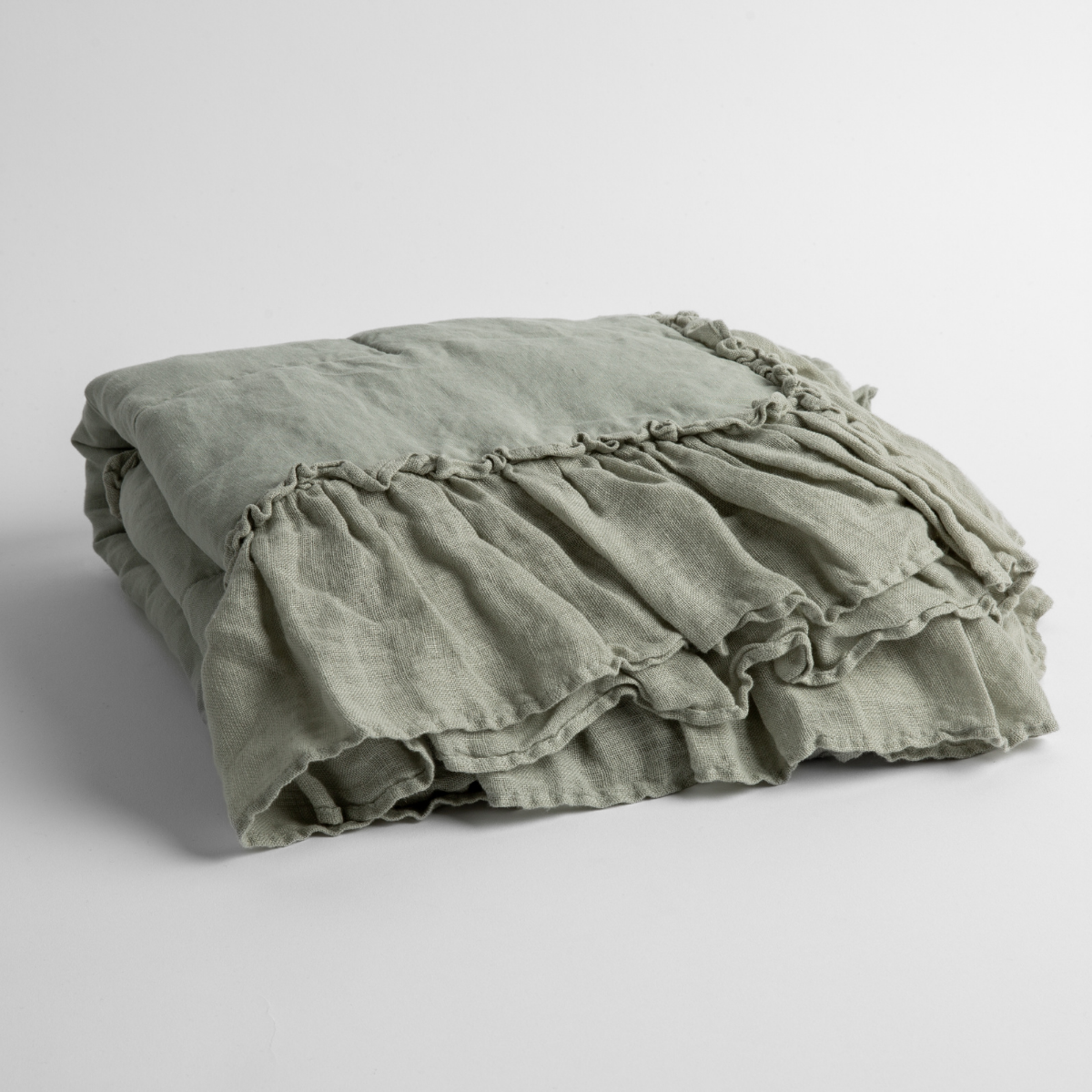 Eucalyptus:   a folded linen with linen whisper ruffled blanket folded and positioned to show the ruffle detail against a white background and slightly overhead. 