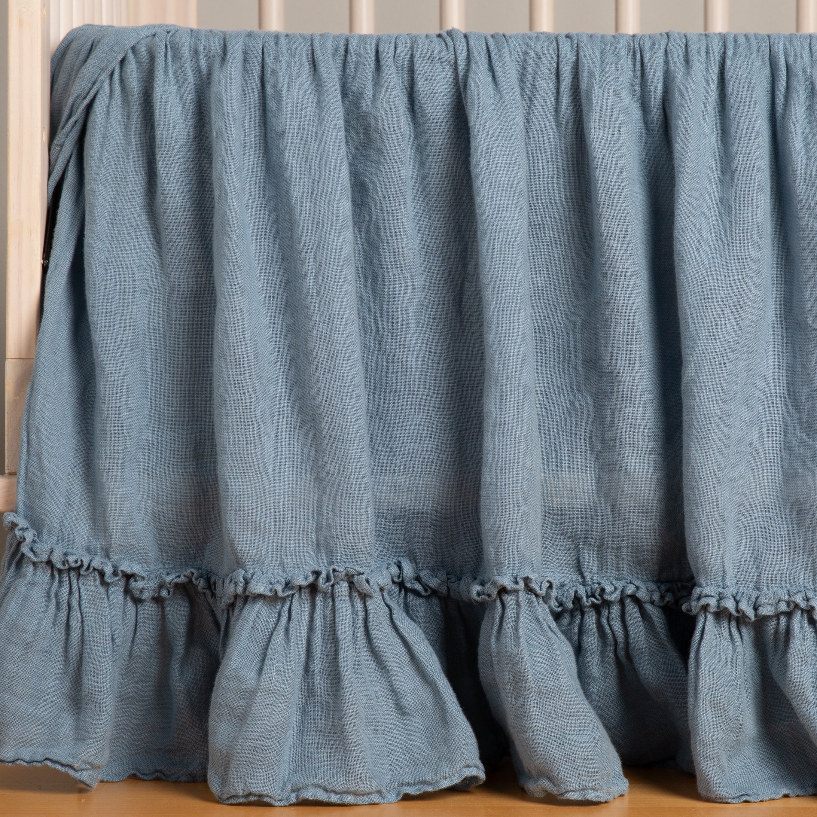 Tahoe Blue: Linen crib skirt in tahoe blue on a wooden crib- side view.