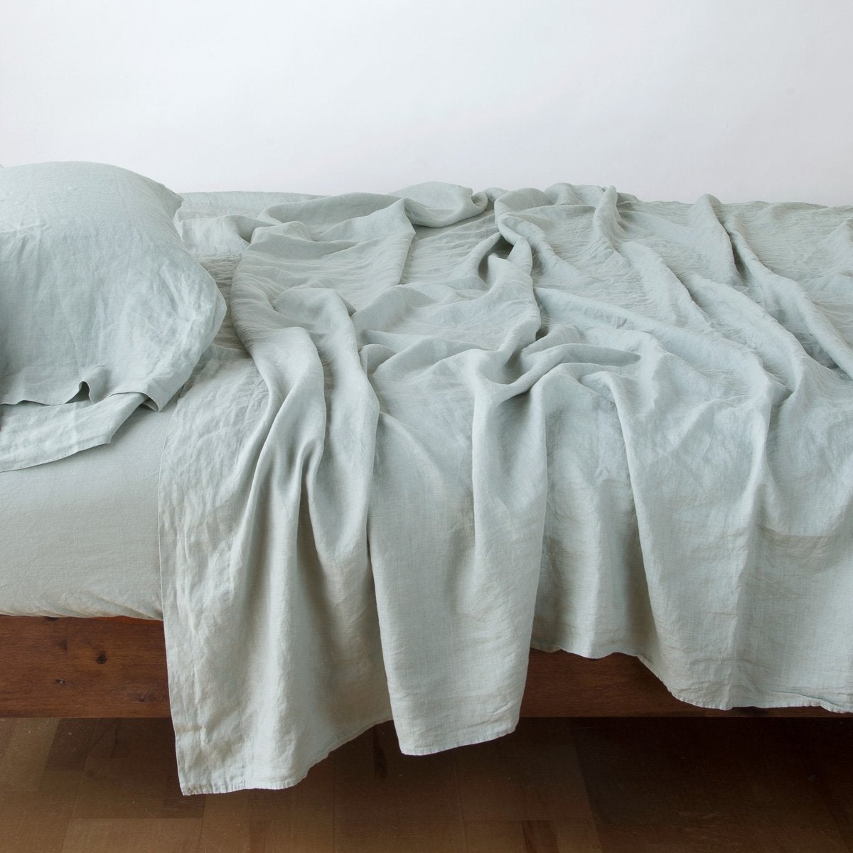 : Linen sleeping pillow in eucalyptus with matching linen sheeting - side view.