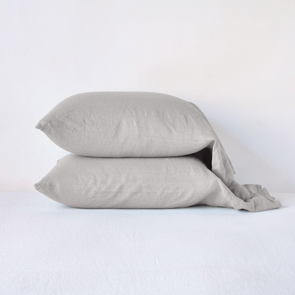 [allvariants]: Two linen slepping pillows in fog, stacked neatly against a plain background - side view.