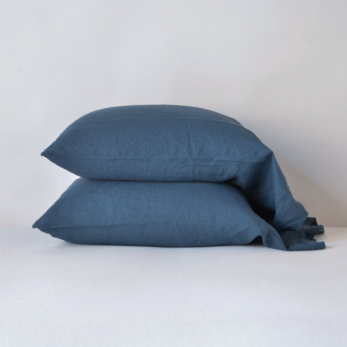 Midnight: Two sleeping pillows neatly stacked against a white background - side view.