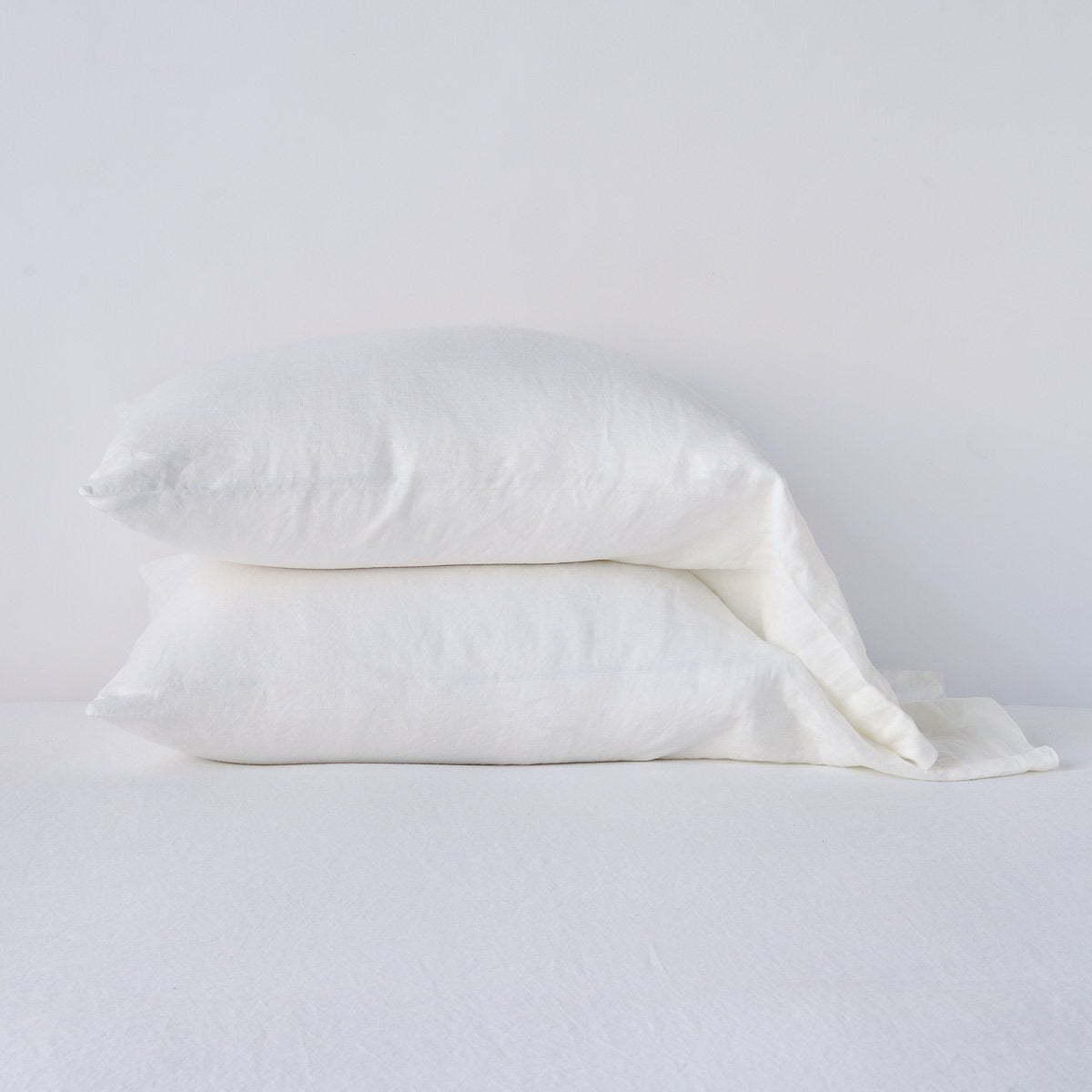 Winter White: Two sleeping pillows neatly stacked against a white background - side view.