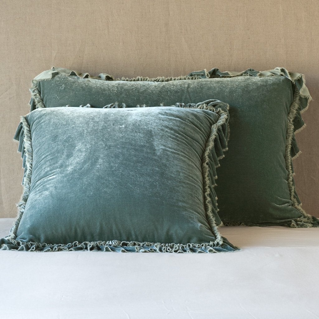 Eucalyptus: shams leaning upright on white sheets against a neutral headboard.