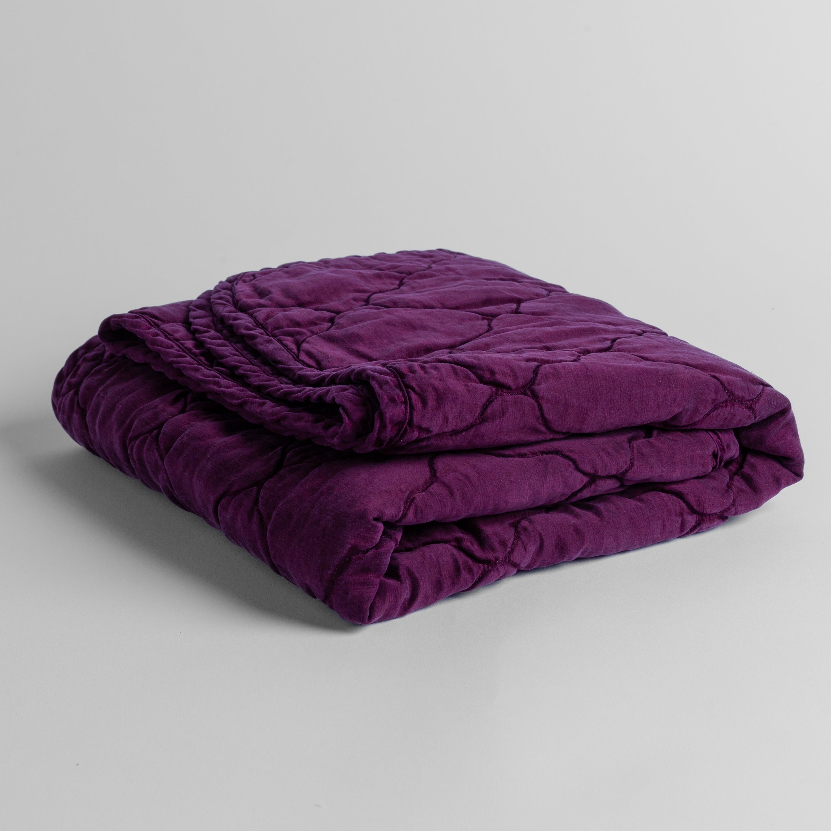 Fig:  quilted charmeuse blanket folded and shown against a white background from a slight overhead angle. 