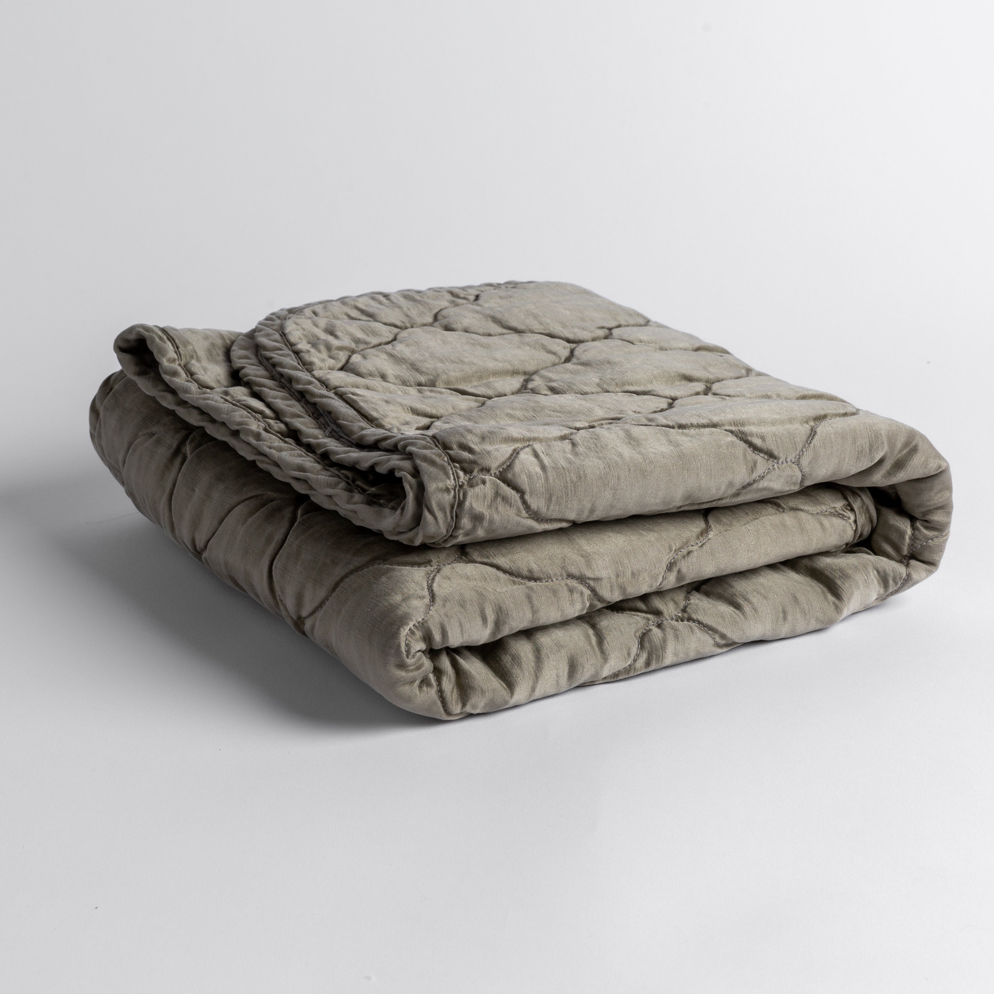 Fog: quilted charmeuse blanket folded and shown against a white background from a slight overhead angle. 