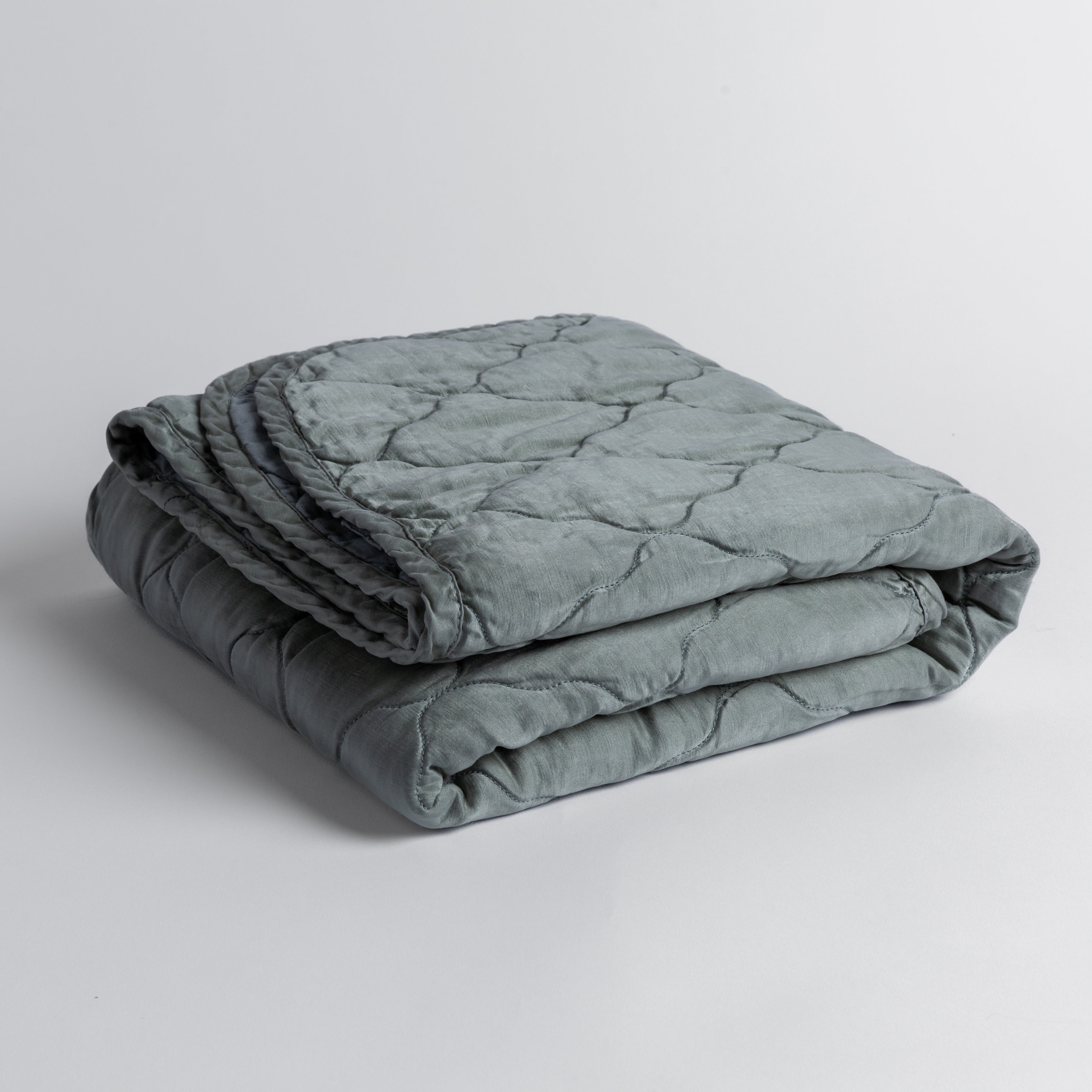 Mineral:  quilted charmeuse blanket folded and shown against a white background from a slight overhead angle. 