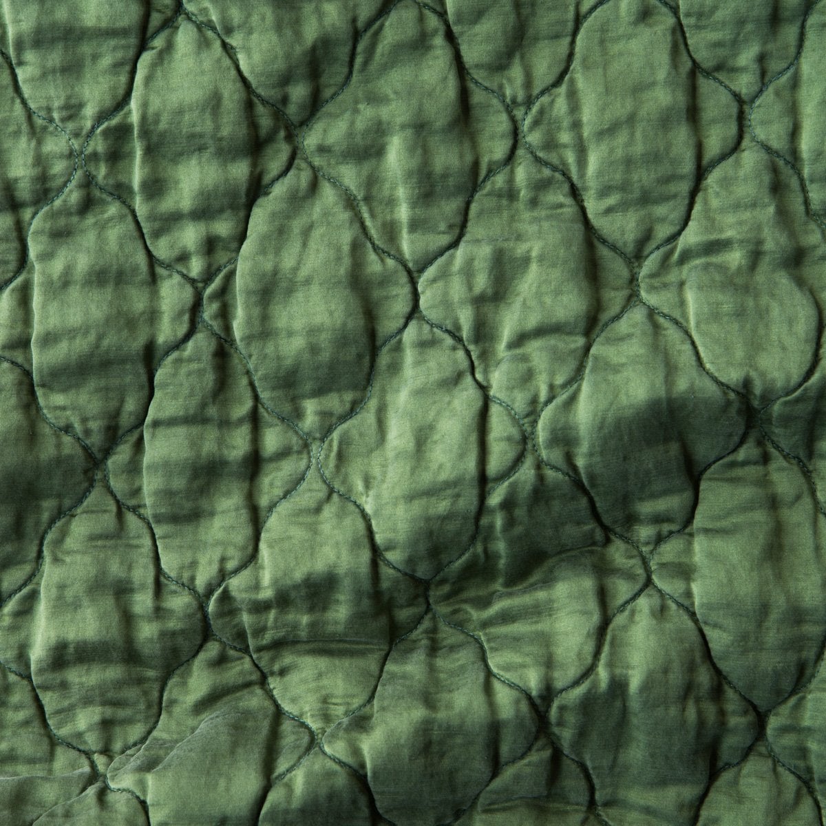 Jade: Close-up of Luna silk charmeuse quilting in jade, a rich, verdant green with subtle blue undertones. 