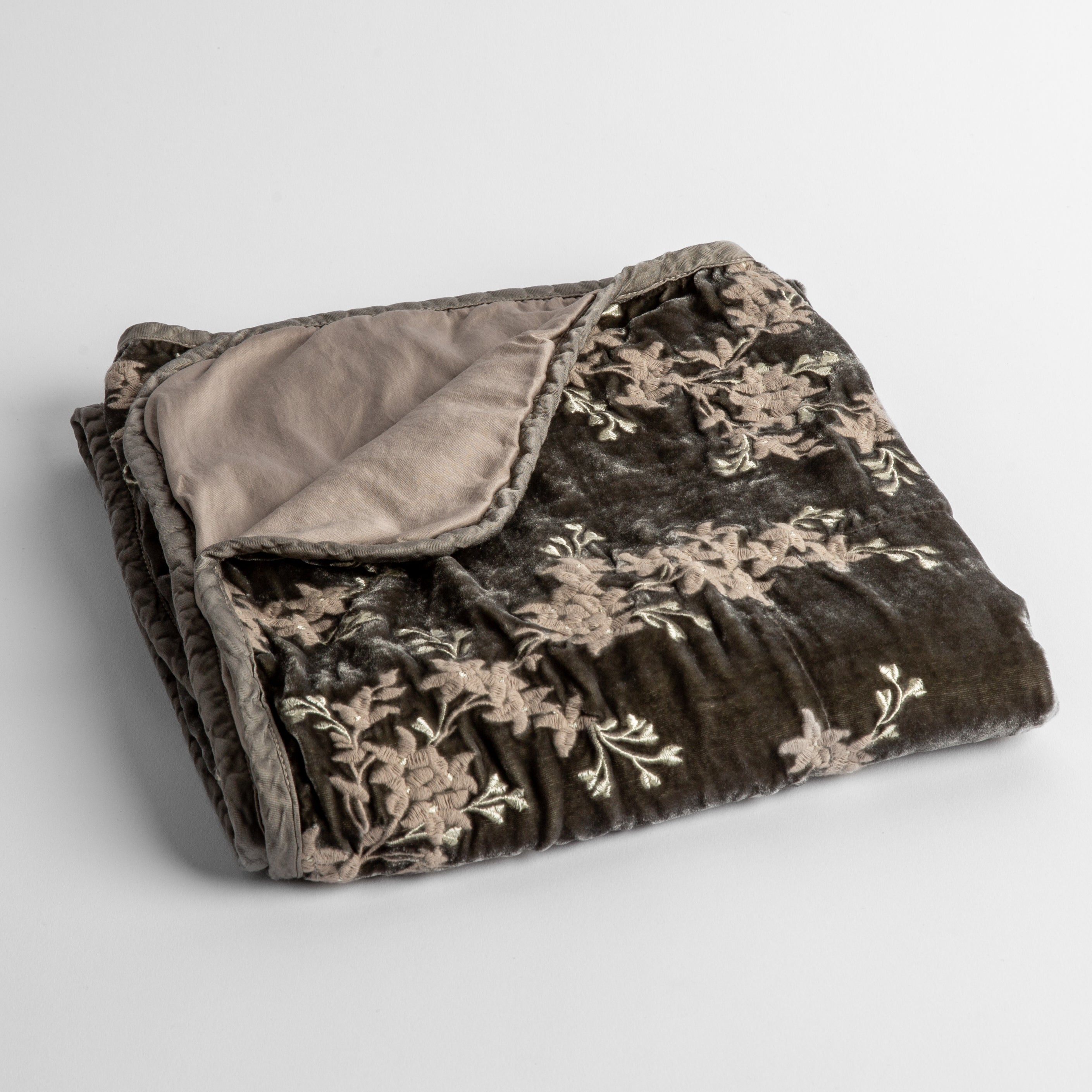 Fog: embroidered silk velvet baby blanket folded with a corner folded back to show the trim and back of the blanket - shot overhead at a slight angle against a white background. 