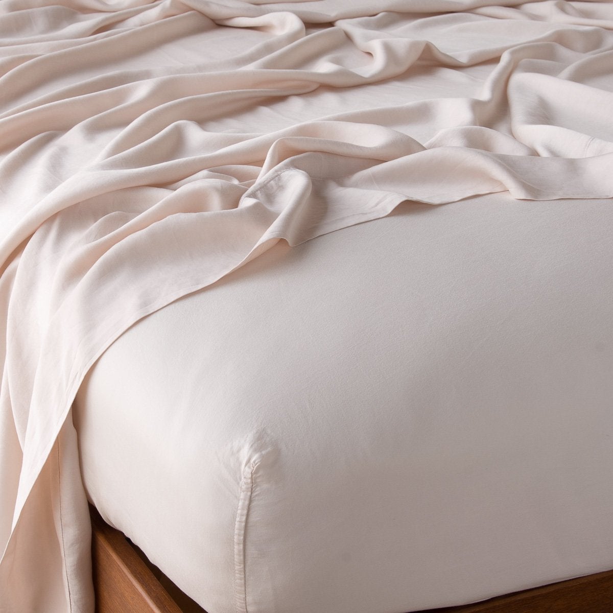 : Madera Luxe fitted sheet in pearl with matching rumpled flat sheet - shown from top corner.