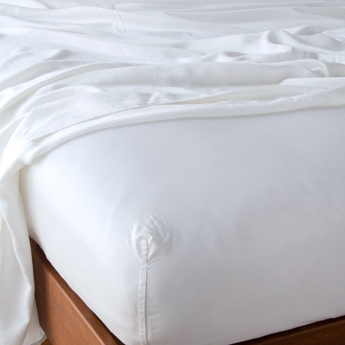 White: fitted sheet with matching rumpled flat sheet - top corner view.