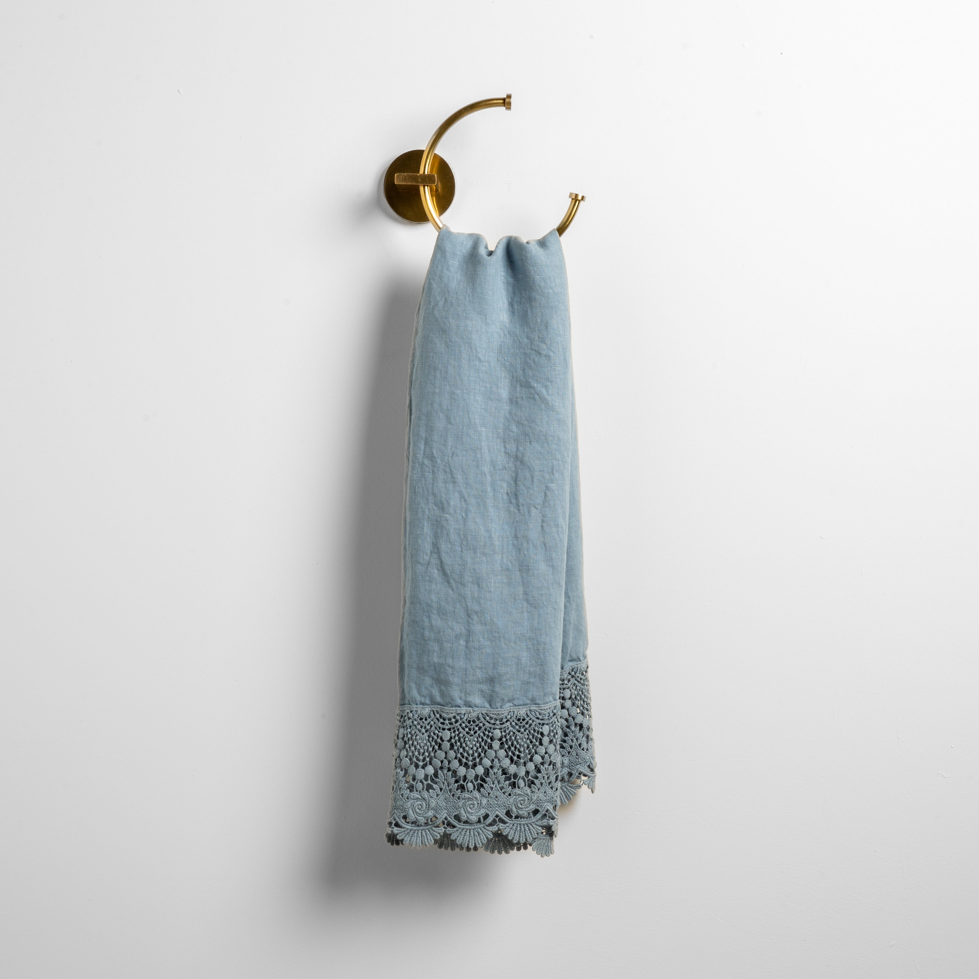 Tahoe Blue: linen with mattine lace trimmed guest towel on a decorative towel ring mounted on a white wall. 
