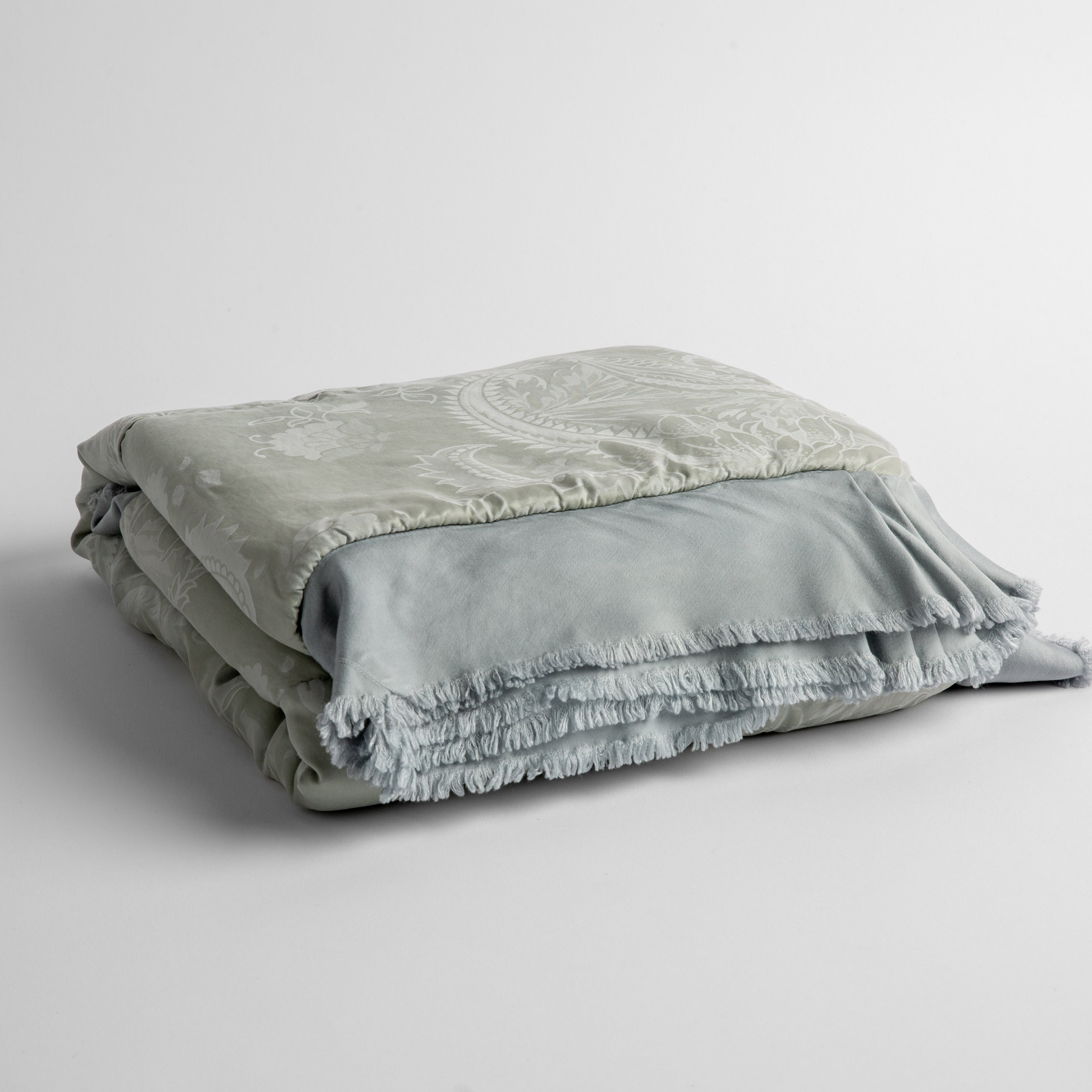 Cloud: a silk and tencel™ jacquard baby blanket folded and shot against a white background with the ruffled trim situated to be visible