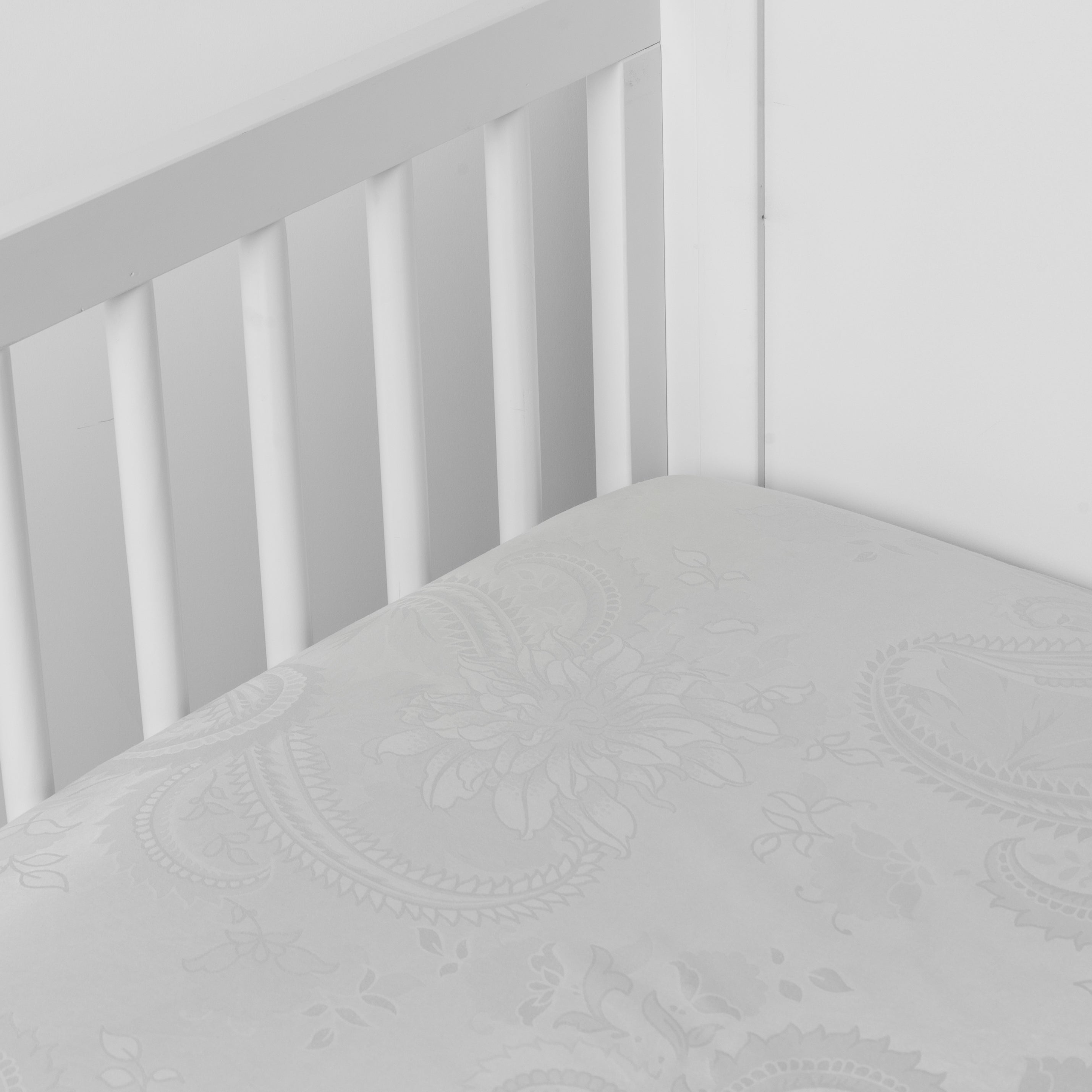 Cloud: a silk and tencel™ crib sheet shown slightly overhread and shot into the corner of a white crib. 