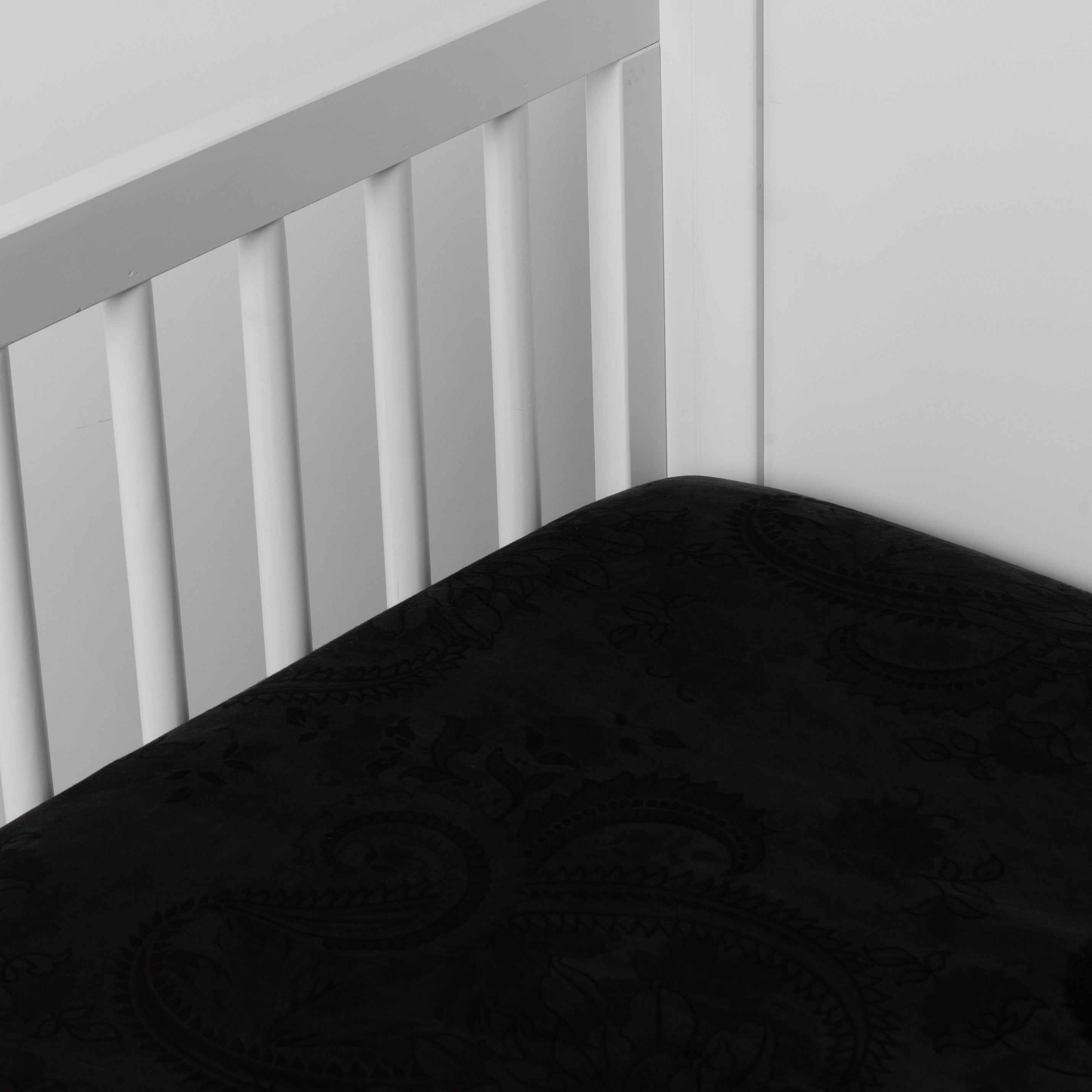 Corvino: a silk and tencel™ crib sheet shown slightly overhread and shot into the corner of a white crib. 