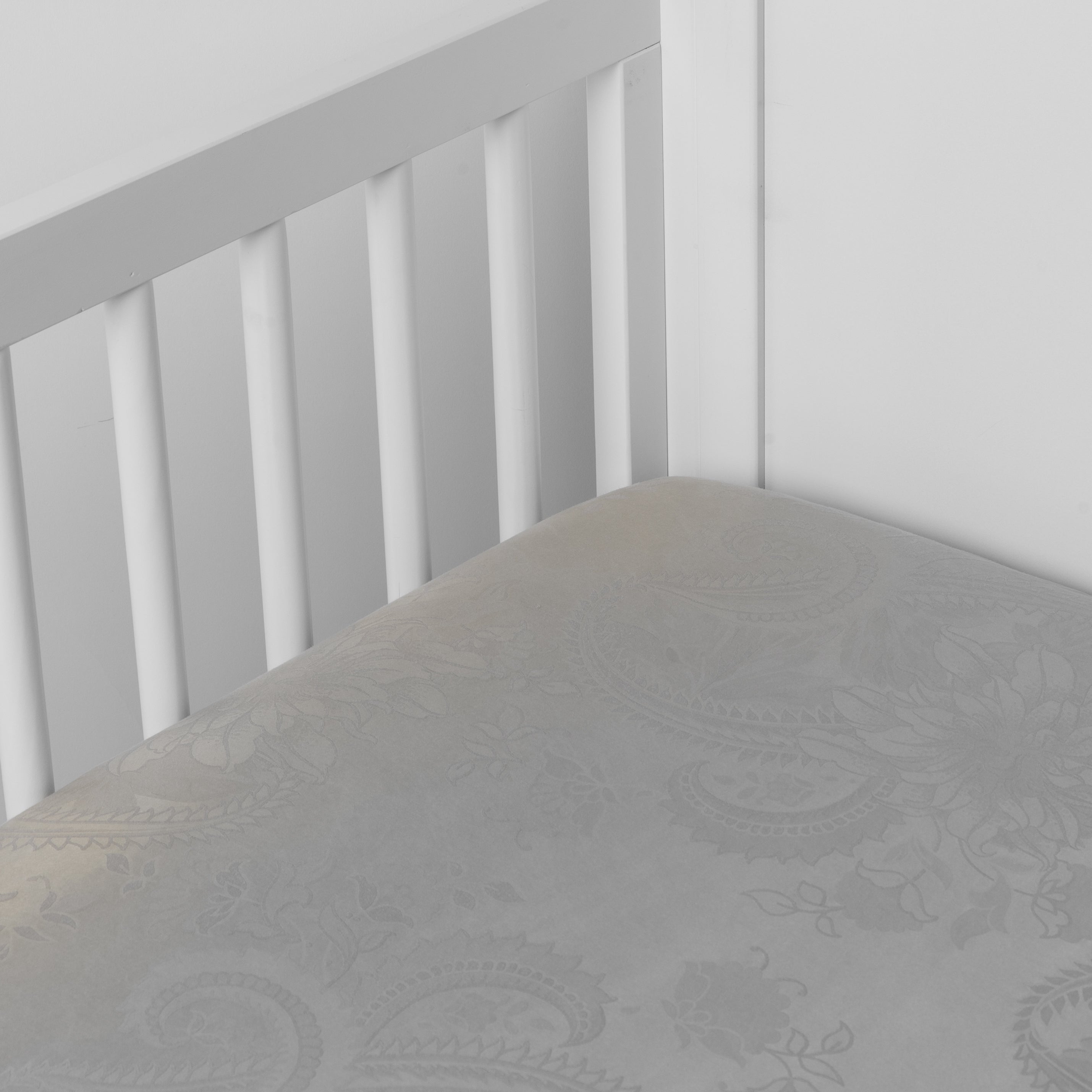 Fog: a silk and tencel™ crib sheet shown slightly overhread and shot into the corner of a white crib. 