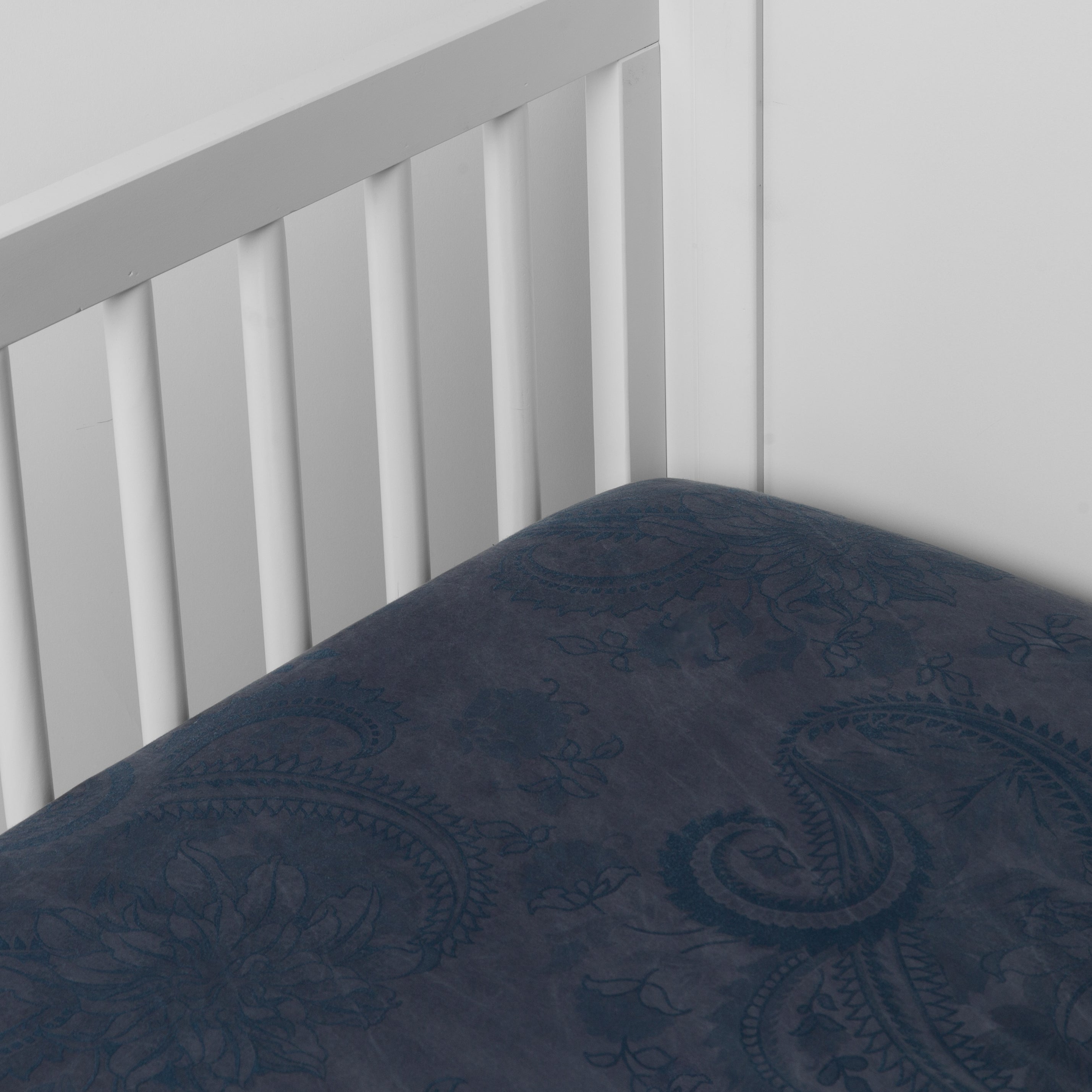 Midnight: a silk and tencel™ crib sheet shown slightly overhread and shot into the corner of a white crib. 