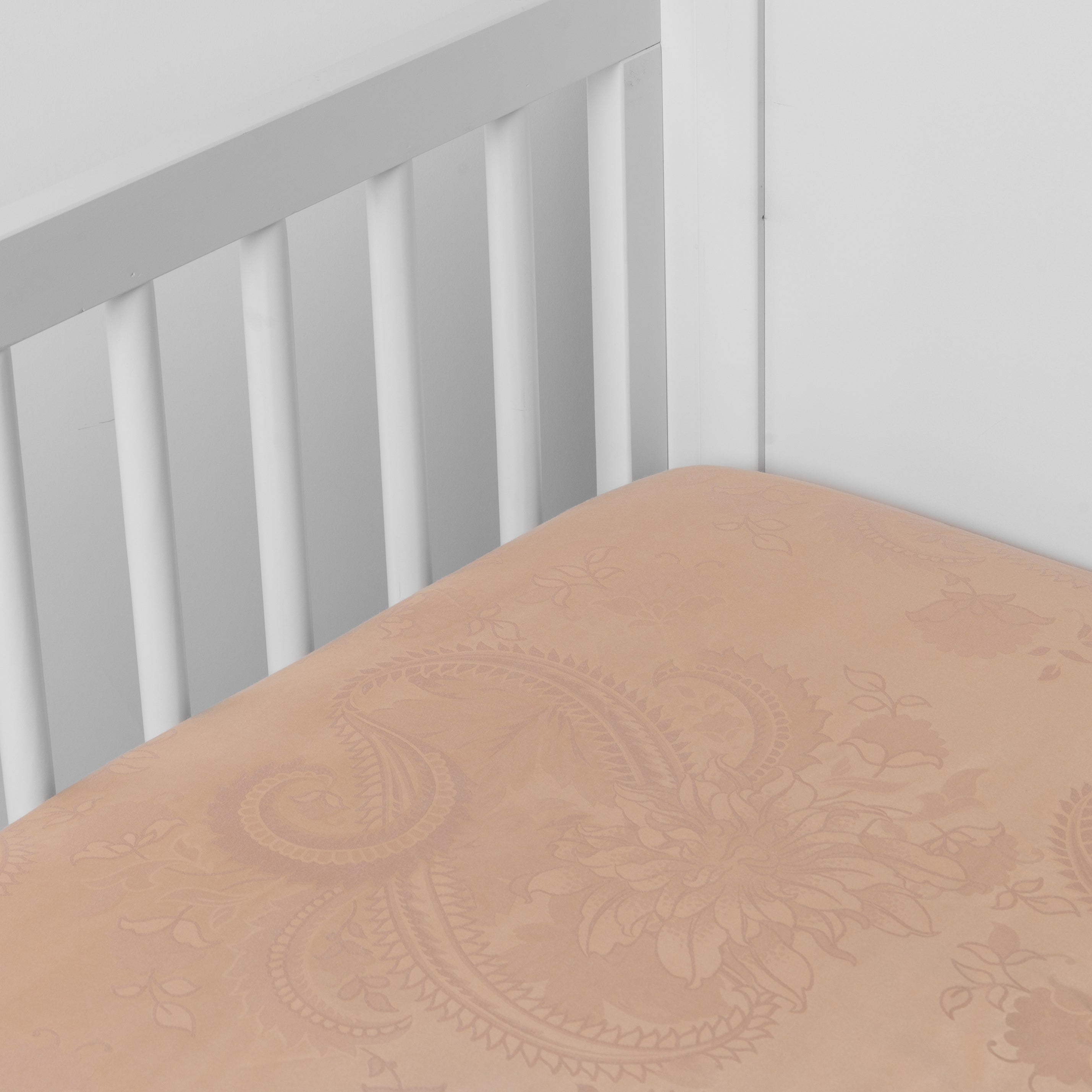 Rouge: a silk and tencel™ crib sheet shown slightly overhread and shot into the corner of a white crib. 