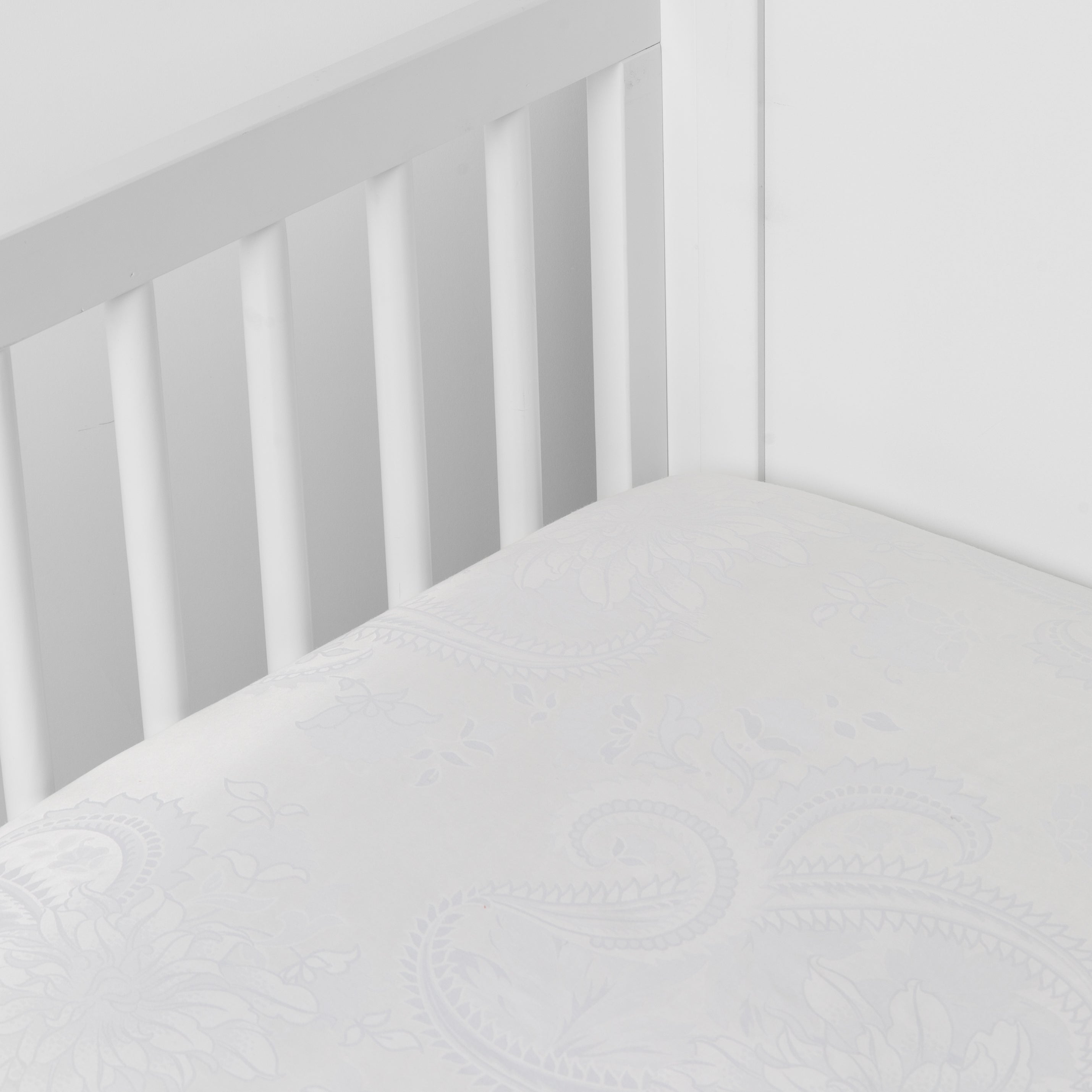 White:  a silk and tencel™ crib sheet shown slightly overhread and shot into the corner of a white crib. 