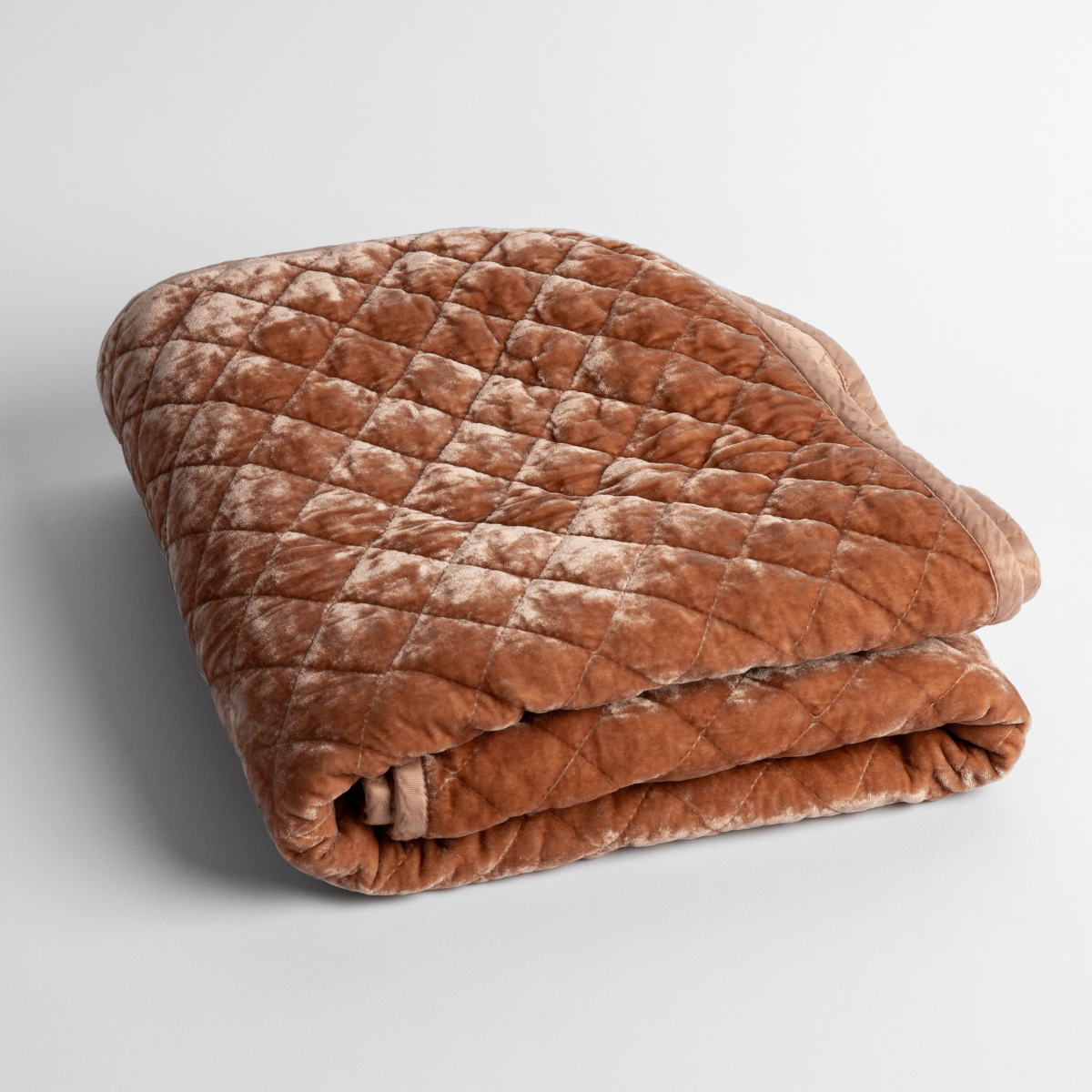 Rouge:   a folded quilted silk velvet baby blanket shown from overhead to showcase quilting  pattern and texture. 
