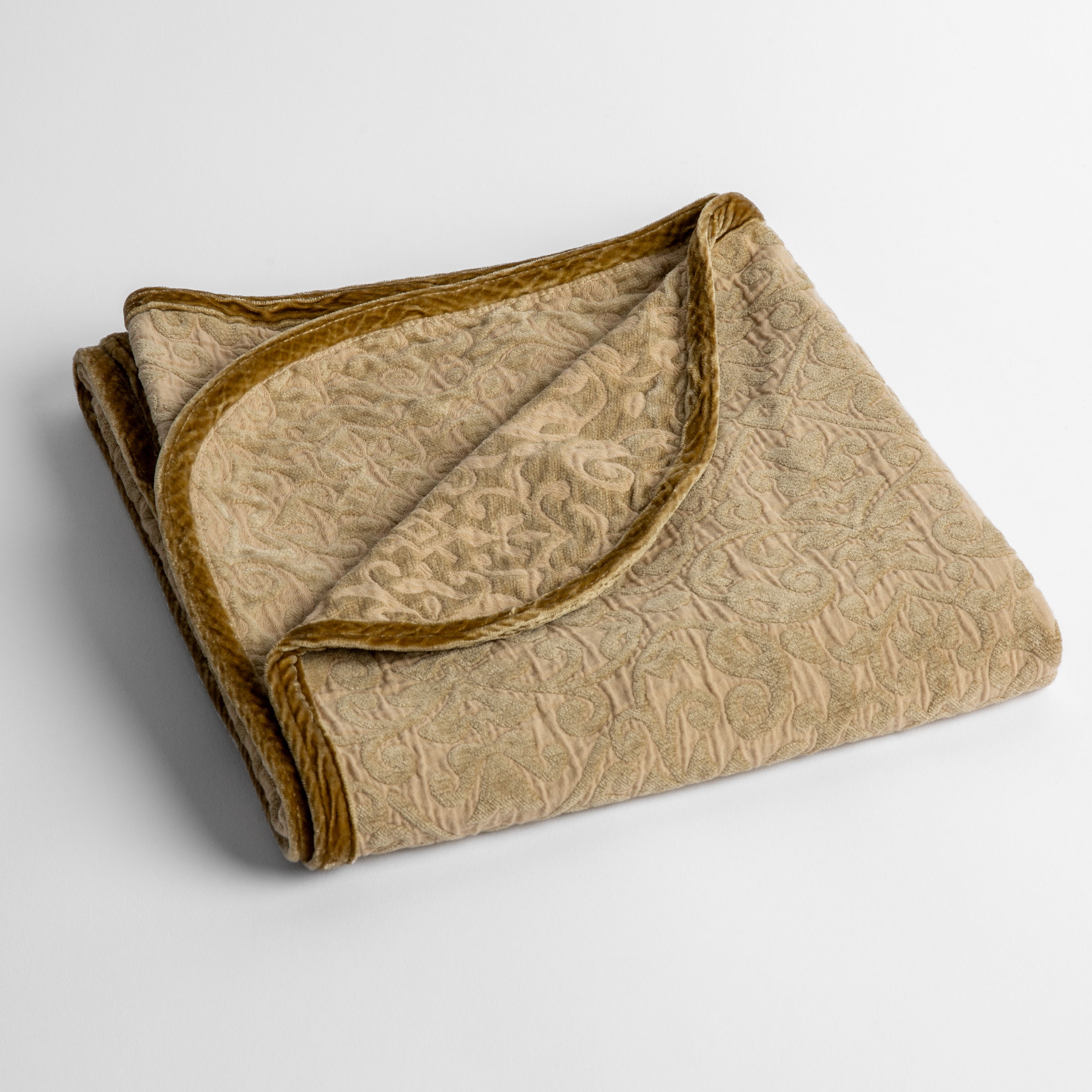 Honeycomb: a folded cotton chenille baby blanket trimmed in silk velvet shot overhead at a slight angle against a white background. 