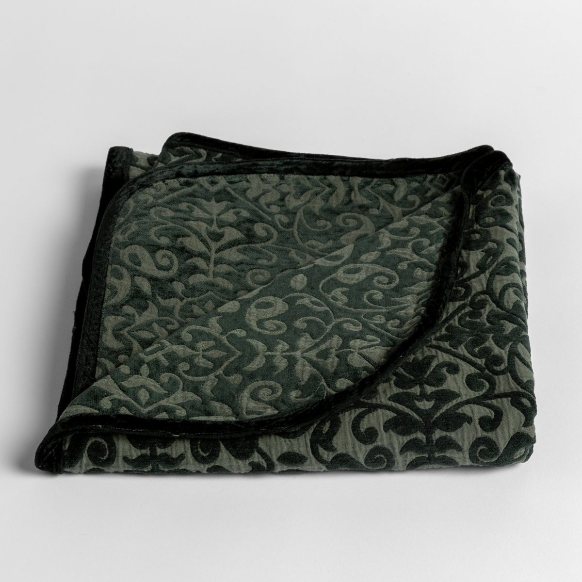 Juniper: cotton chenille baby blanket folded with a corner peeled back showing the pattern reversed and silk velvet trim. 