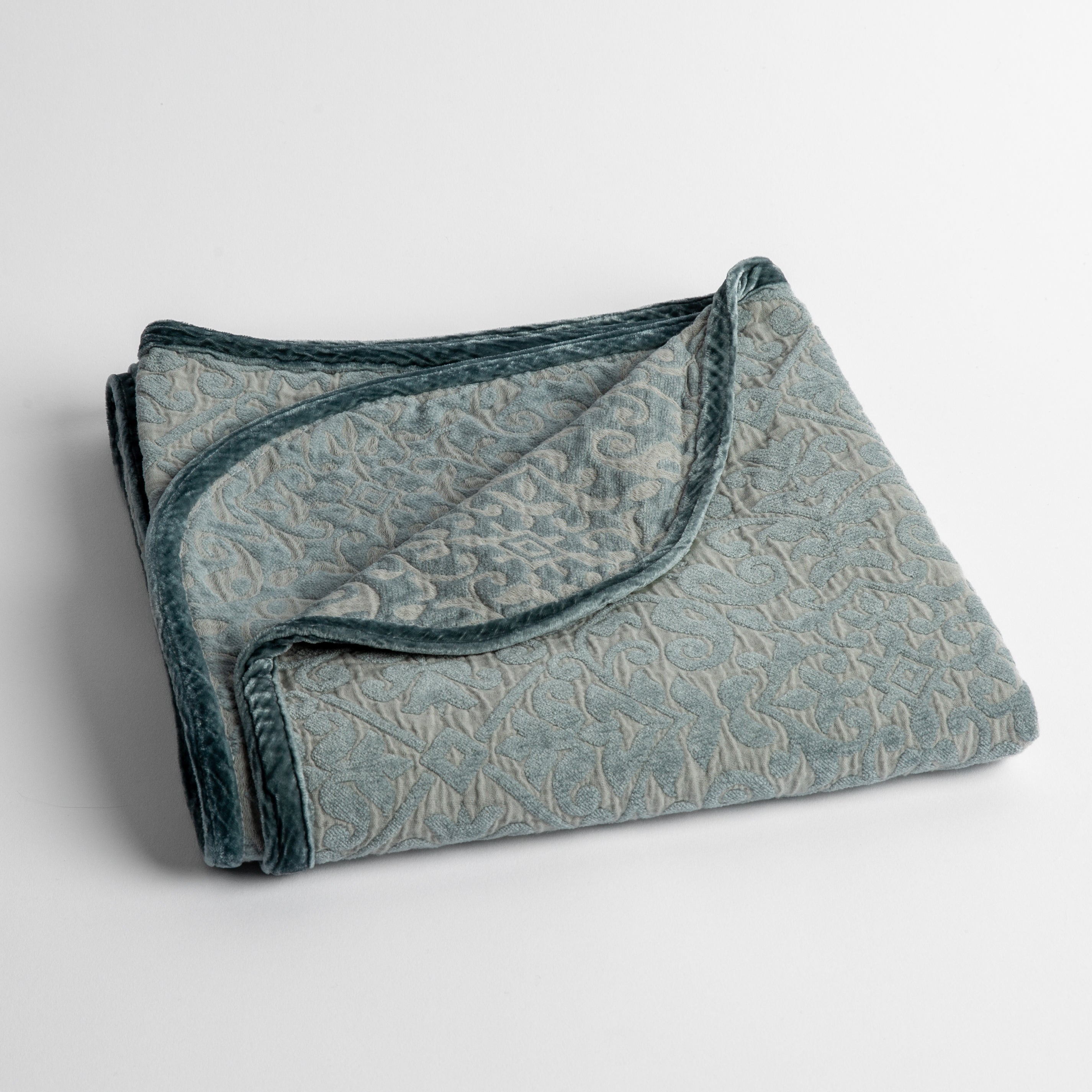 Mineral: a folded cotton chenille baby blanket trimmed in silk velvet shot overhead at a slight angle against a white background. 