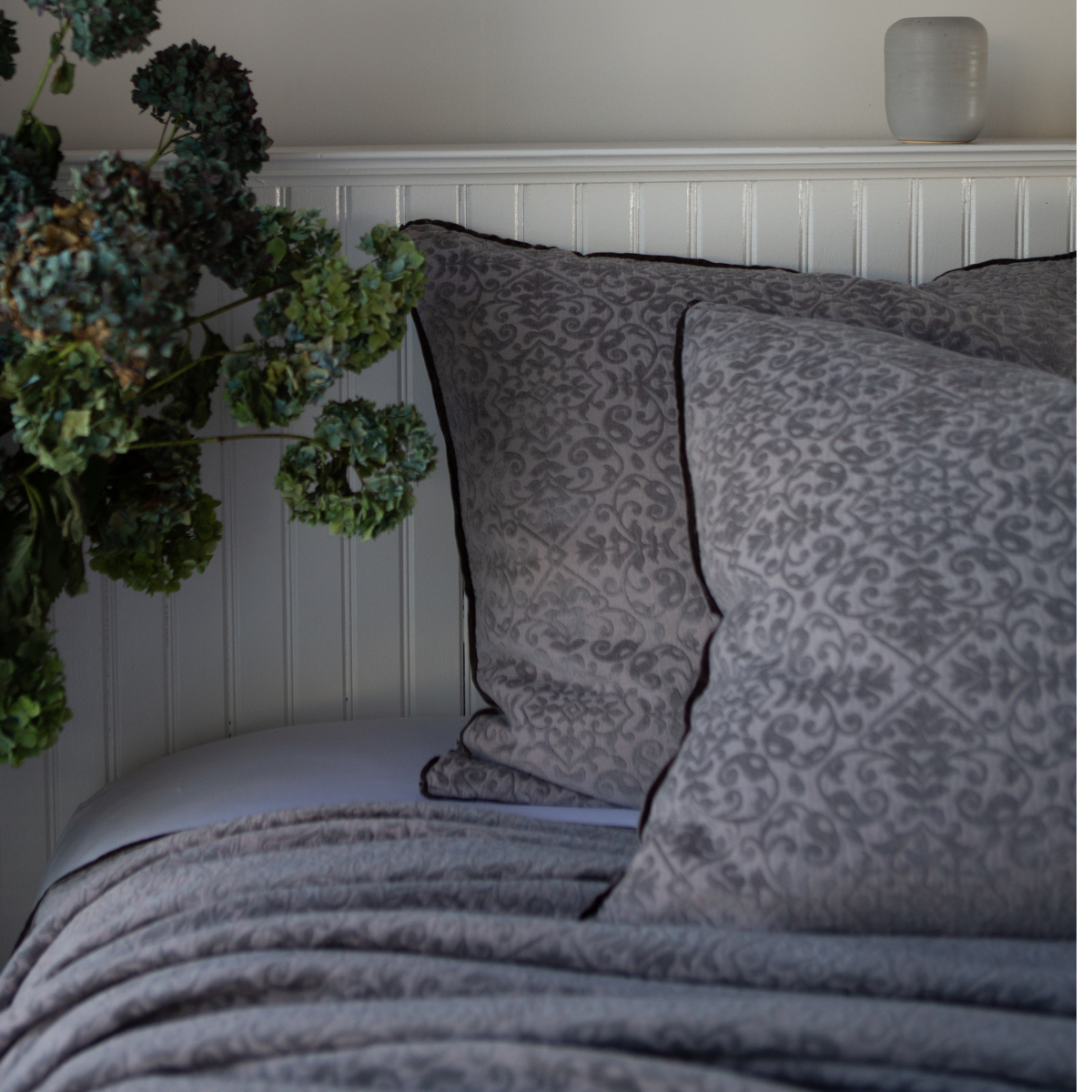 [allvariants]: Vienna shams and coverlet in moonlight against a white beadboard wall. Cropped head-on angle showcases silk velvet trim detail.