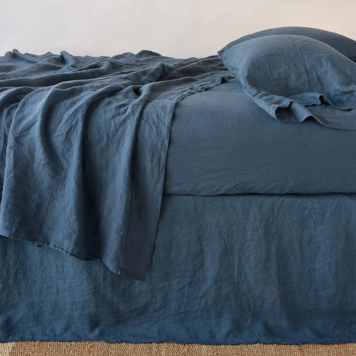 [allvariants]: Austin bed skirt in midnight shown from the side on a bed with monochromatic sheeting, highlighting its tailored, ungathered style.