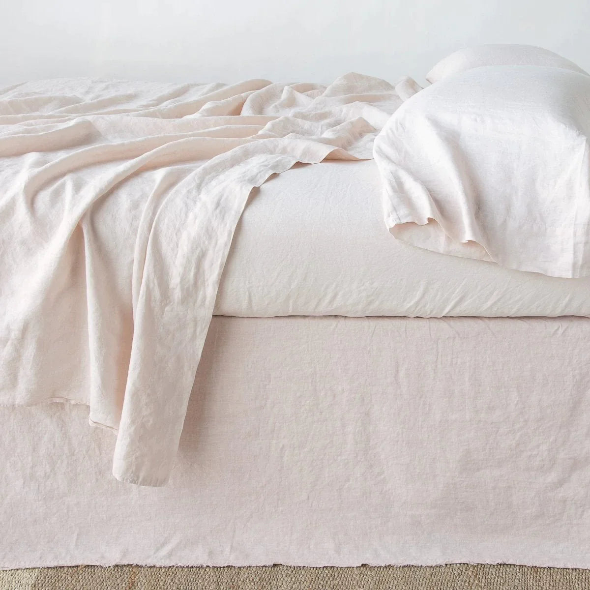 Pearl: Austin bed skirt in pearl shown from the side on a bed with monochromatic sheeting, highlighting its tailored, ungathered style.