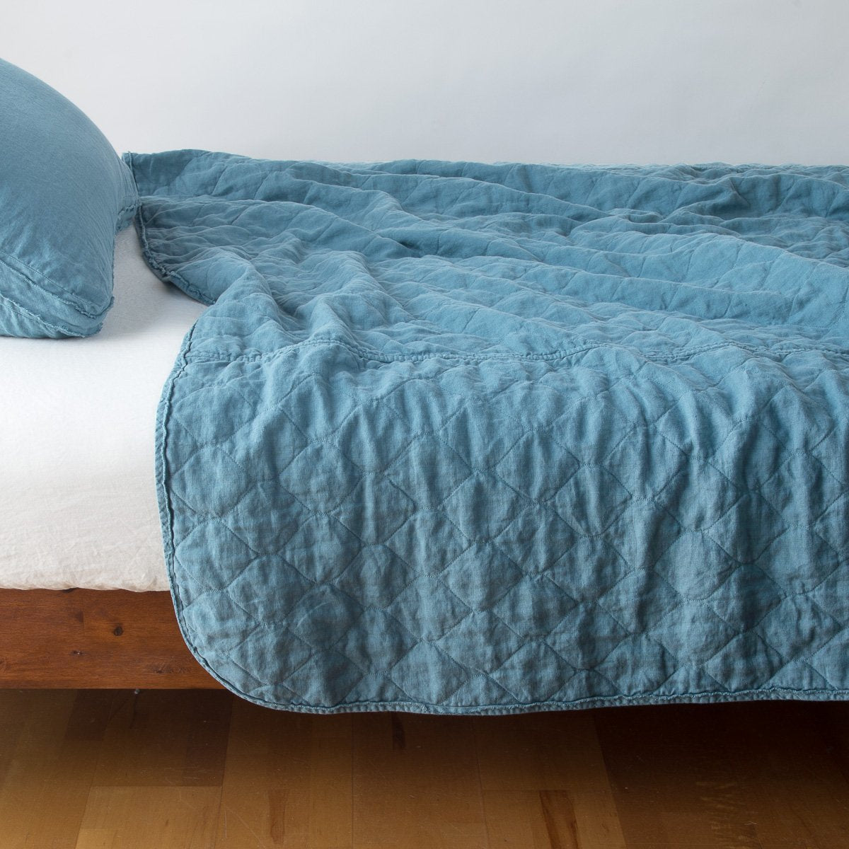 Cenote: quilted midweight linen coverlet on a bed - side view.