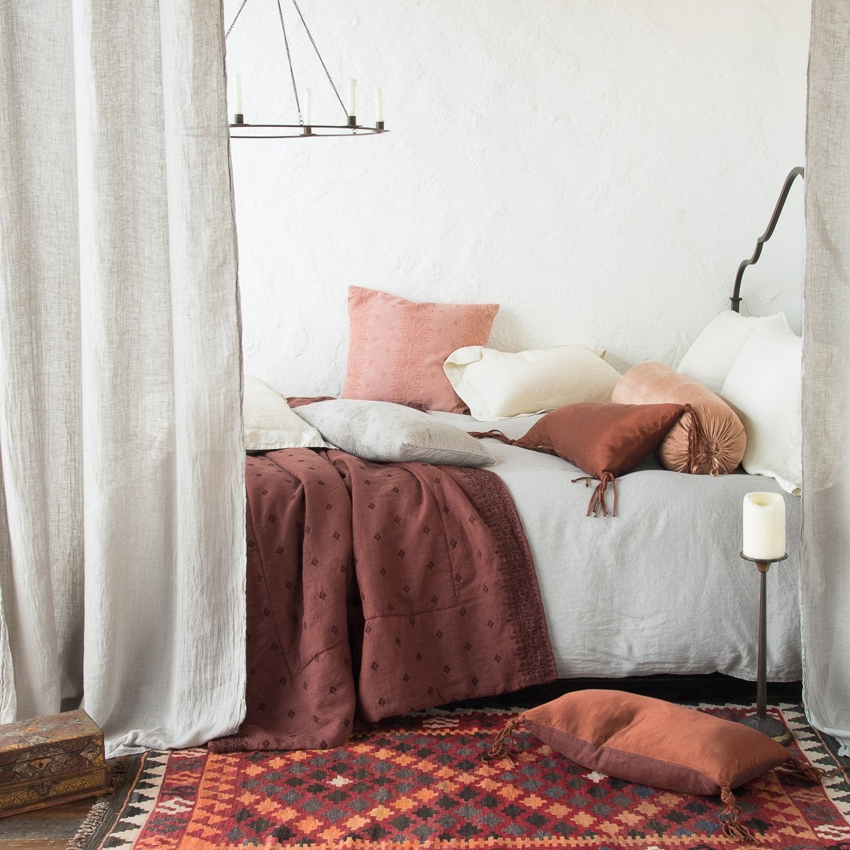 [allvariants]: Linen duvet cover in cloud, layered under rumpled, blue, brown, and pink tones in linen and charmeuse, with a geometric rug and wrought-iron room accents - side view.