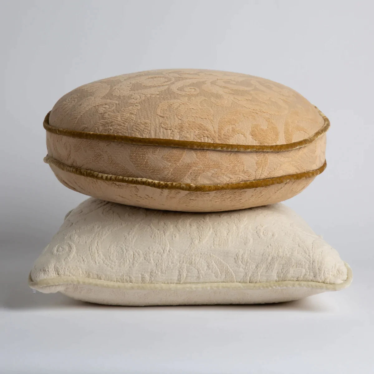 [allvariants]: Organic cotton damask throw pillows stacked with round pillow in honeycomb on top of square pillow in parchment. 