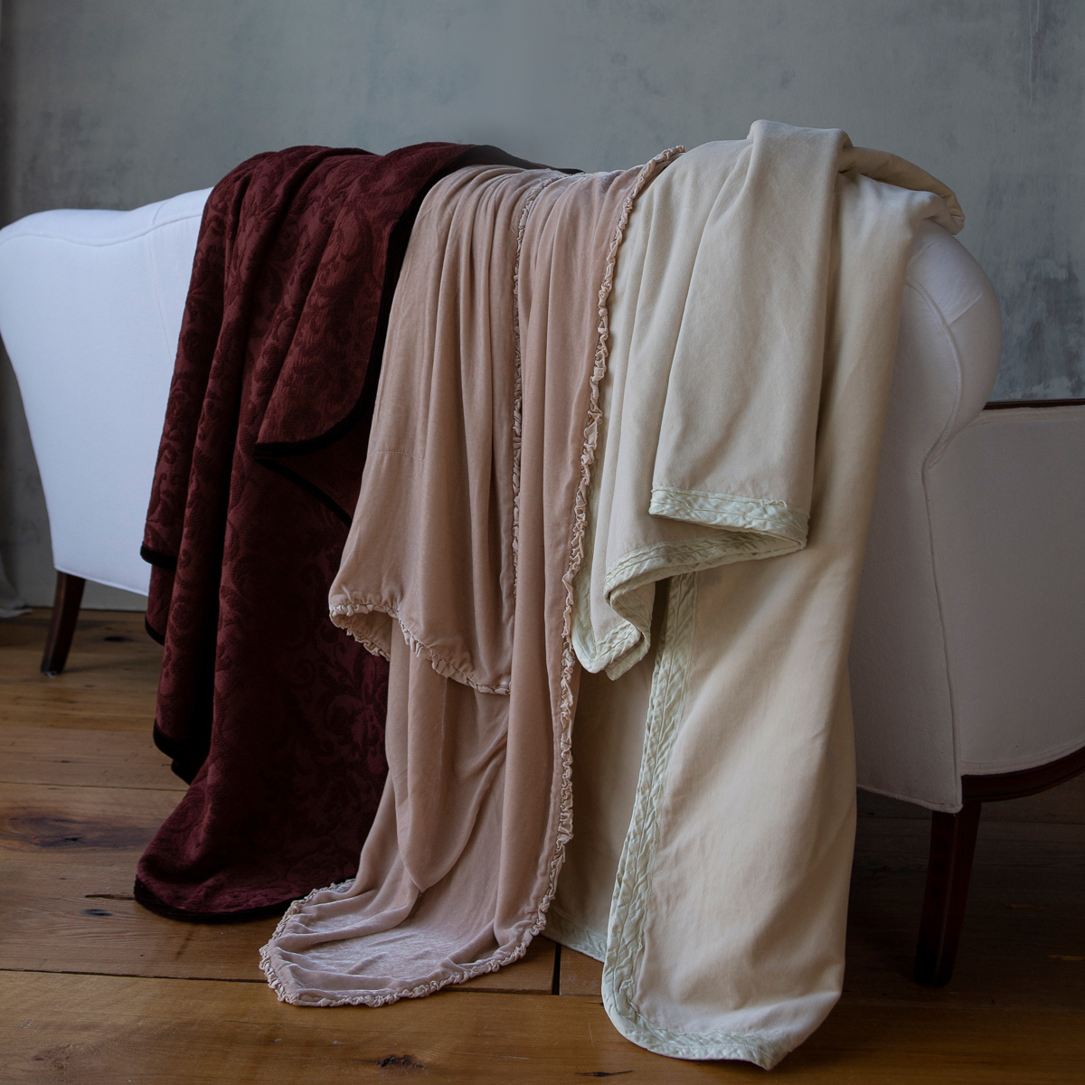 : harlow throw blanket in parchment on far right with two other throw blankets draped over the back of a white couch. 