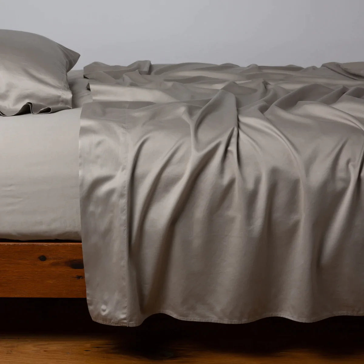 Fog: Cotton sateen sleeping pillow, on a bed with matching sheets - side view.
