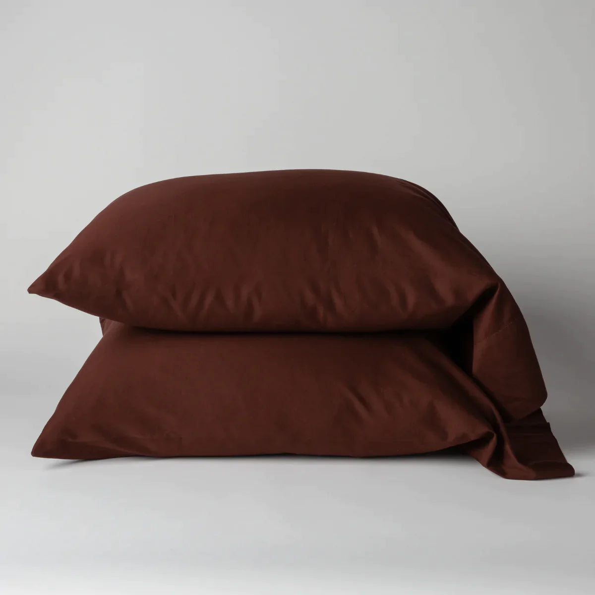 Mahogany: Two cotton sateen sleeping pillows, stacked neatly against a white backdrop - side view.