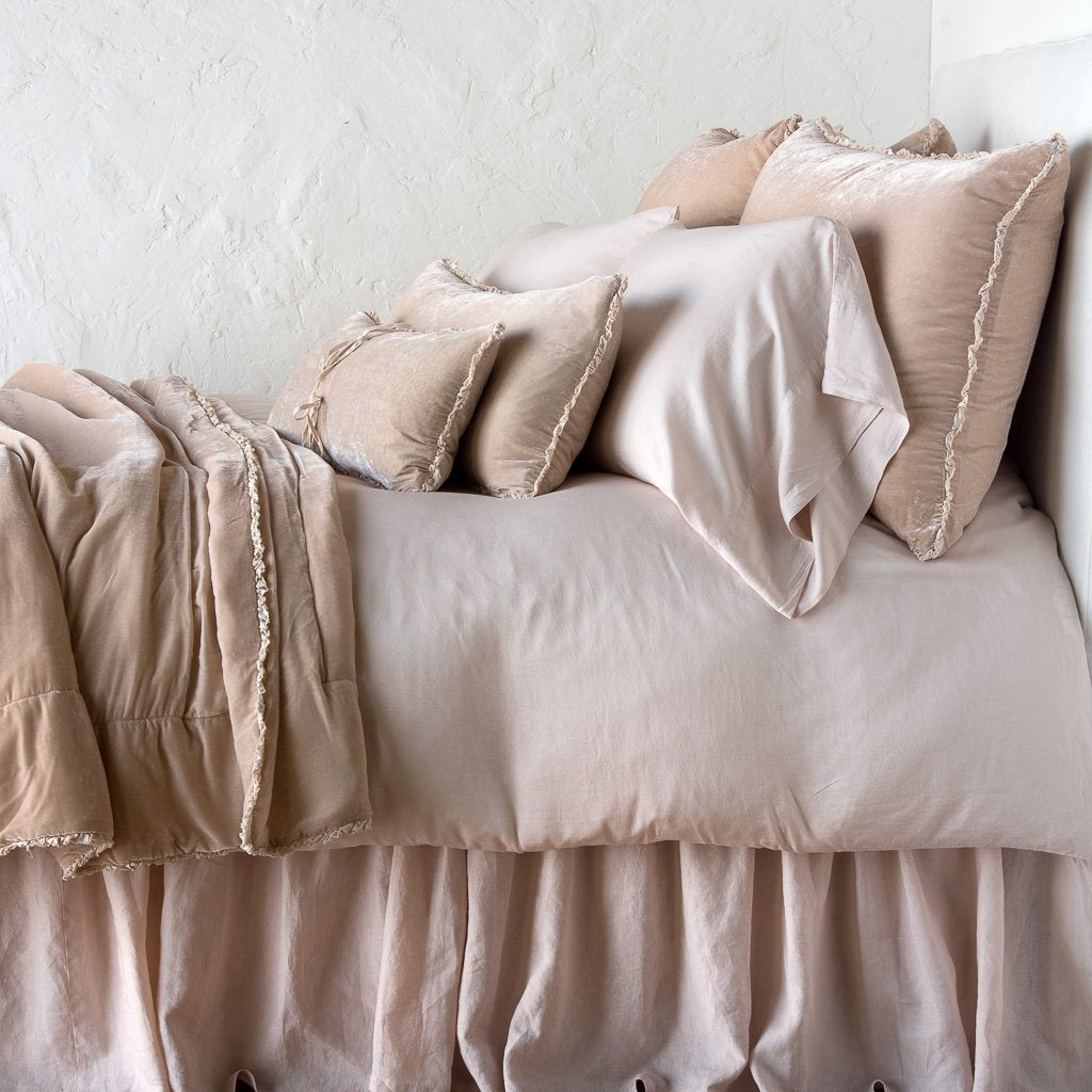 Pearl: Silk velvet throw blanket with petite ruffle, draped across a monochromatic bed - side view.