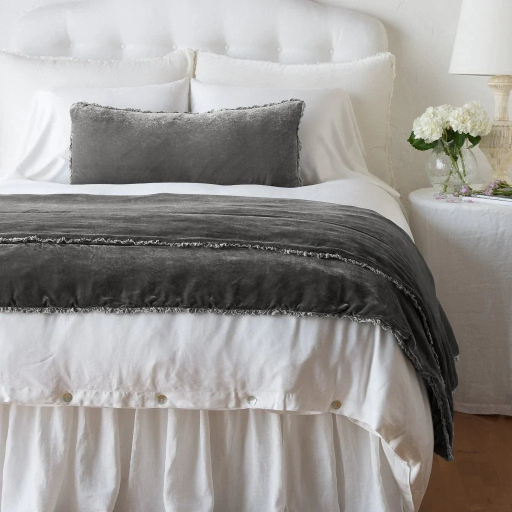 Fog: Silk velvet shams with a petite ruffle on a white bed, stacked behind sleeping and throw pillows - view from end of bed.