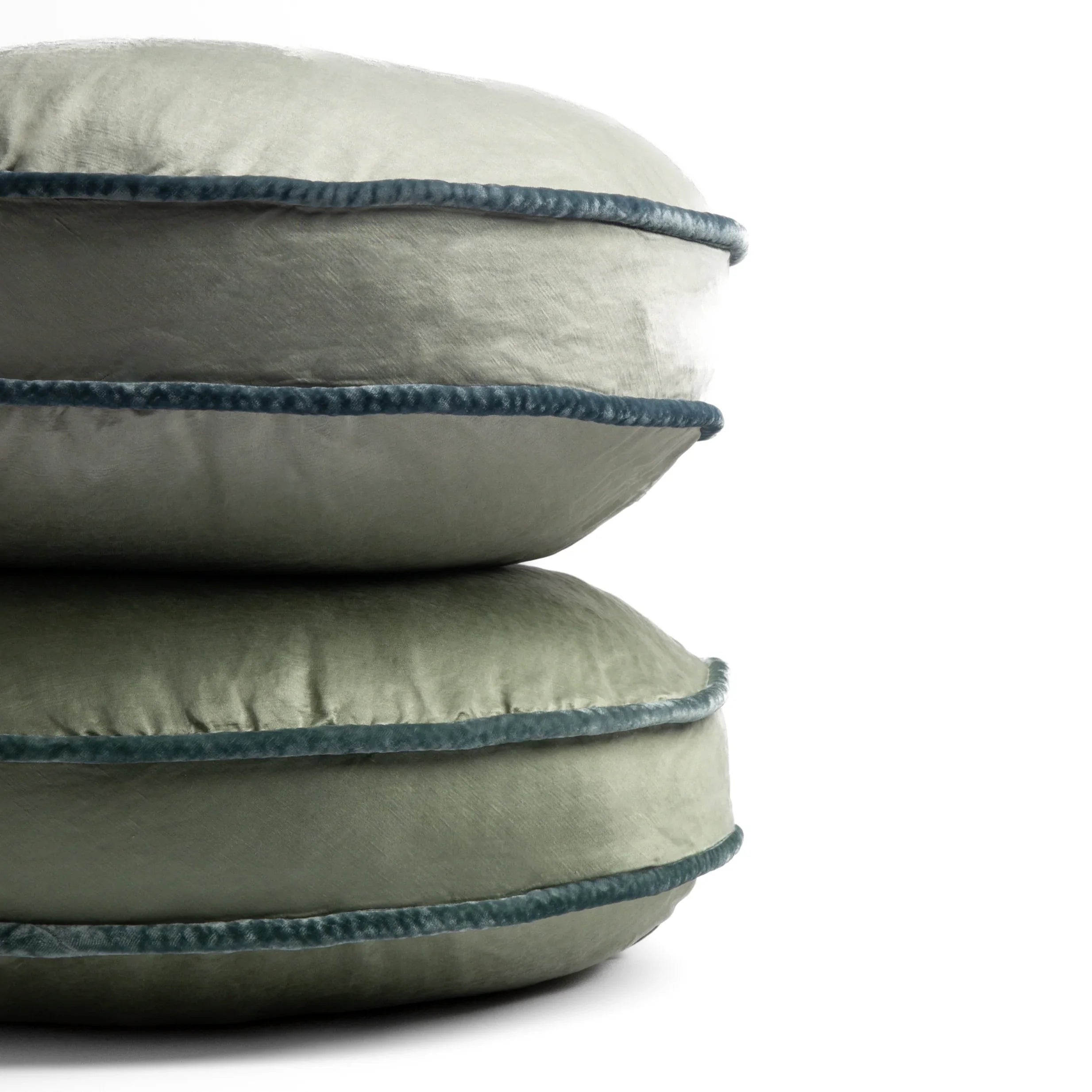 [allvariants]: two 18-inch round pillows stacked against a white background, showing the silk velvet trim on the pillow gussets — Mineral and Eucalyptus.