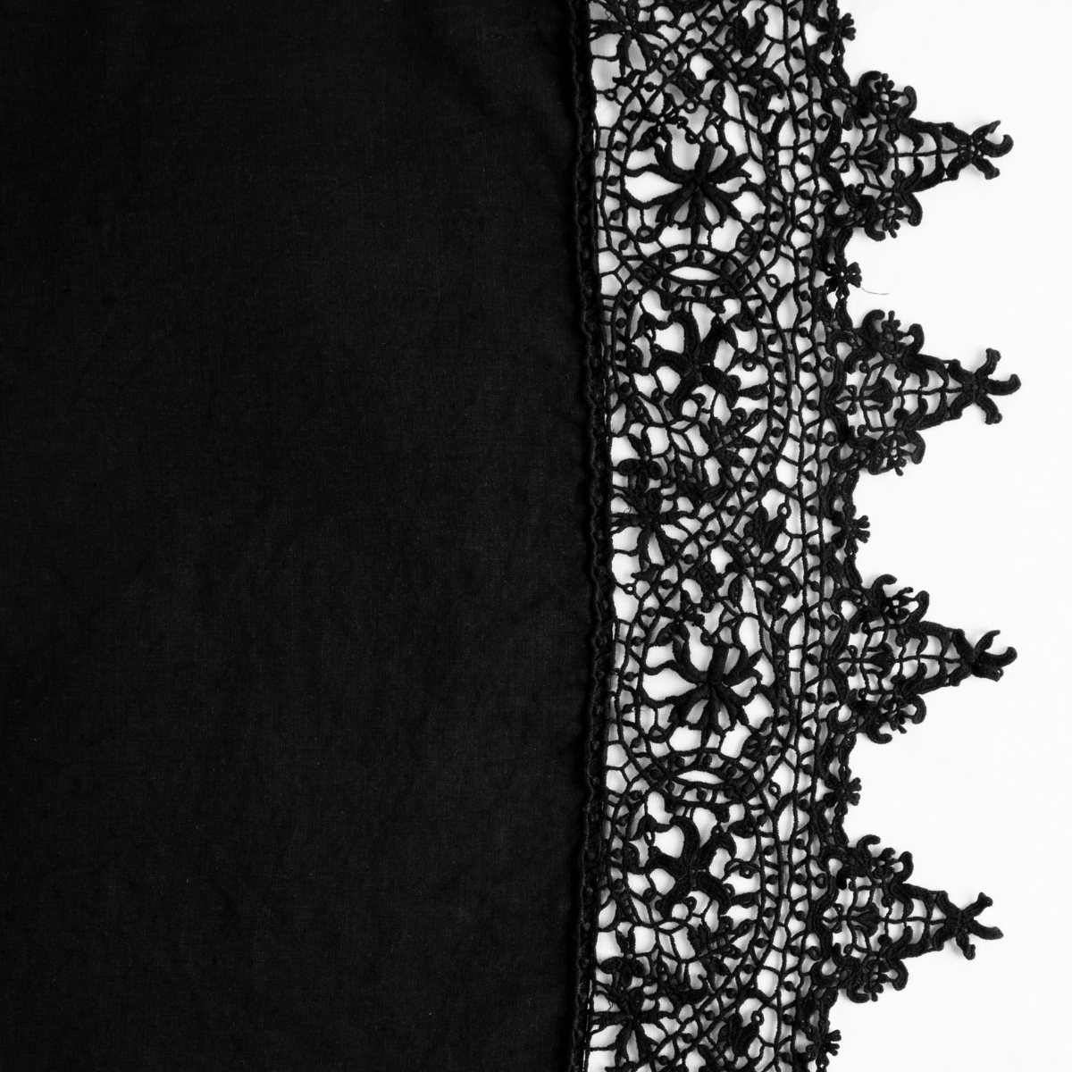 Corvino: A close up of lace trimmed linen fabric in Corvino, a black tone