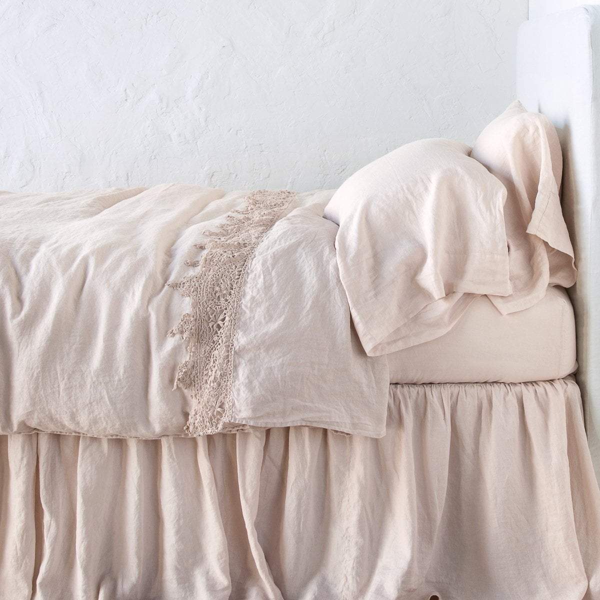Pearl: Lace trimmed linen flat sheet folded back over monochromatic linen bed - side view. 