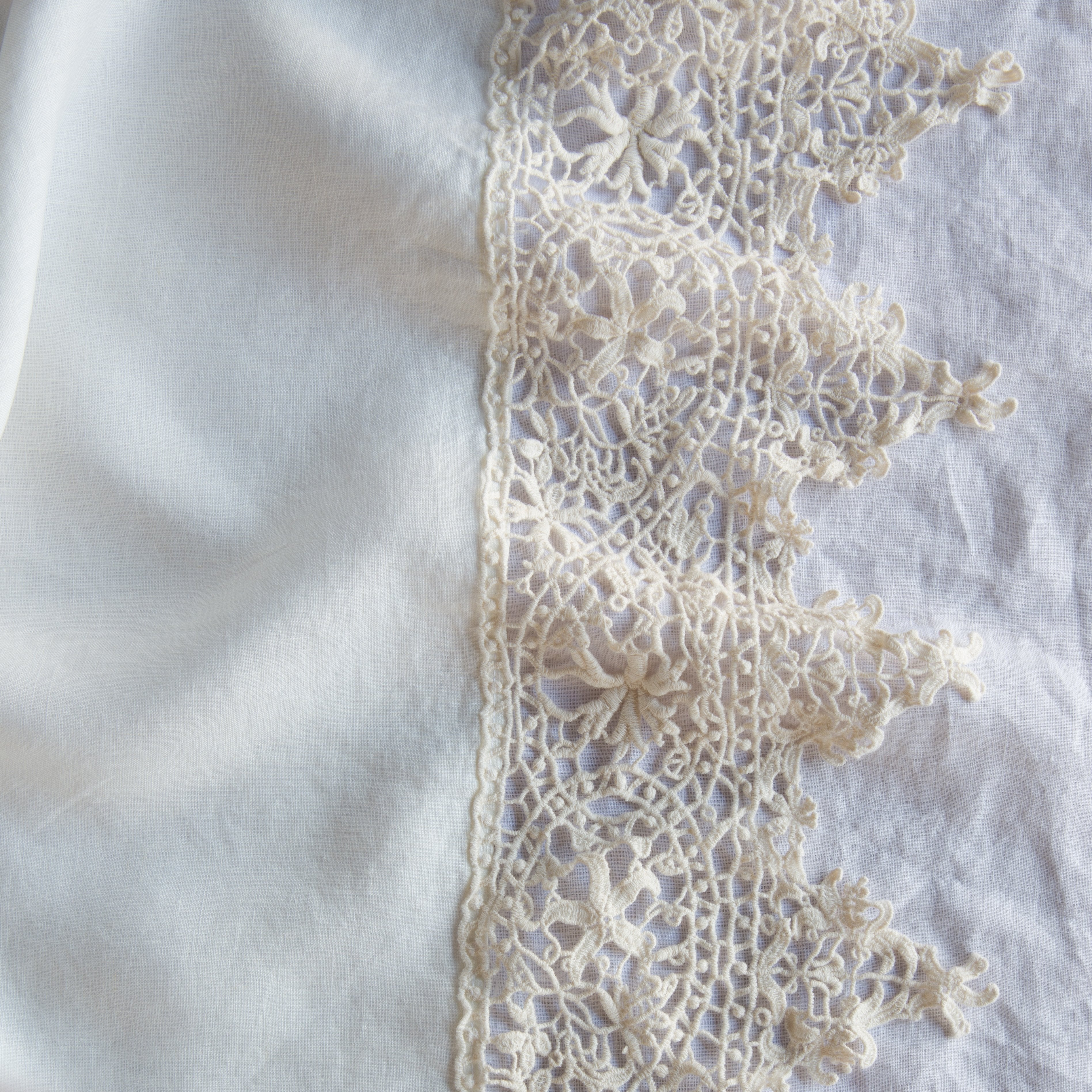 Winter White: A close up of Frida, an antique cotton lace trim on a linen body, shown in winter white, softer and warmer in tone than classic white.